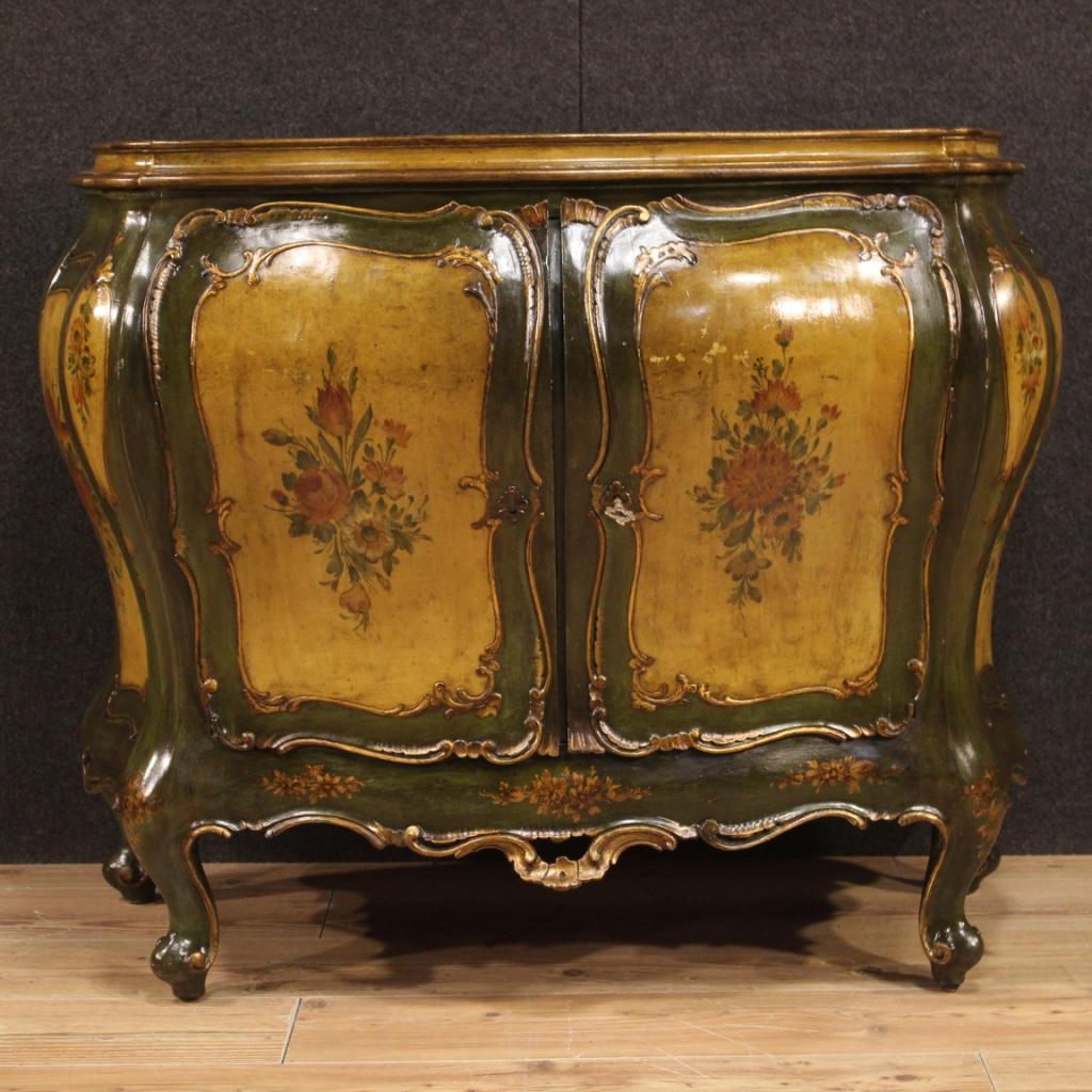 Venetian sideboard from the first half of the 20th century. Moved and rounded furniture in carved, lacquered, gilded and hand painted wood with very pleasant floral decorations. Sideboard with two doors that offers inside two shelves, of good