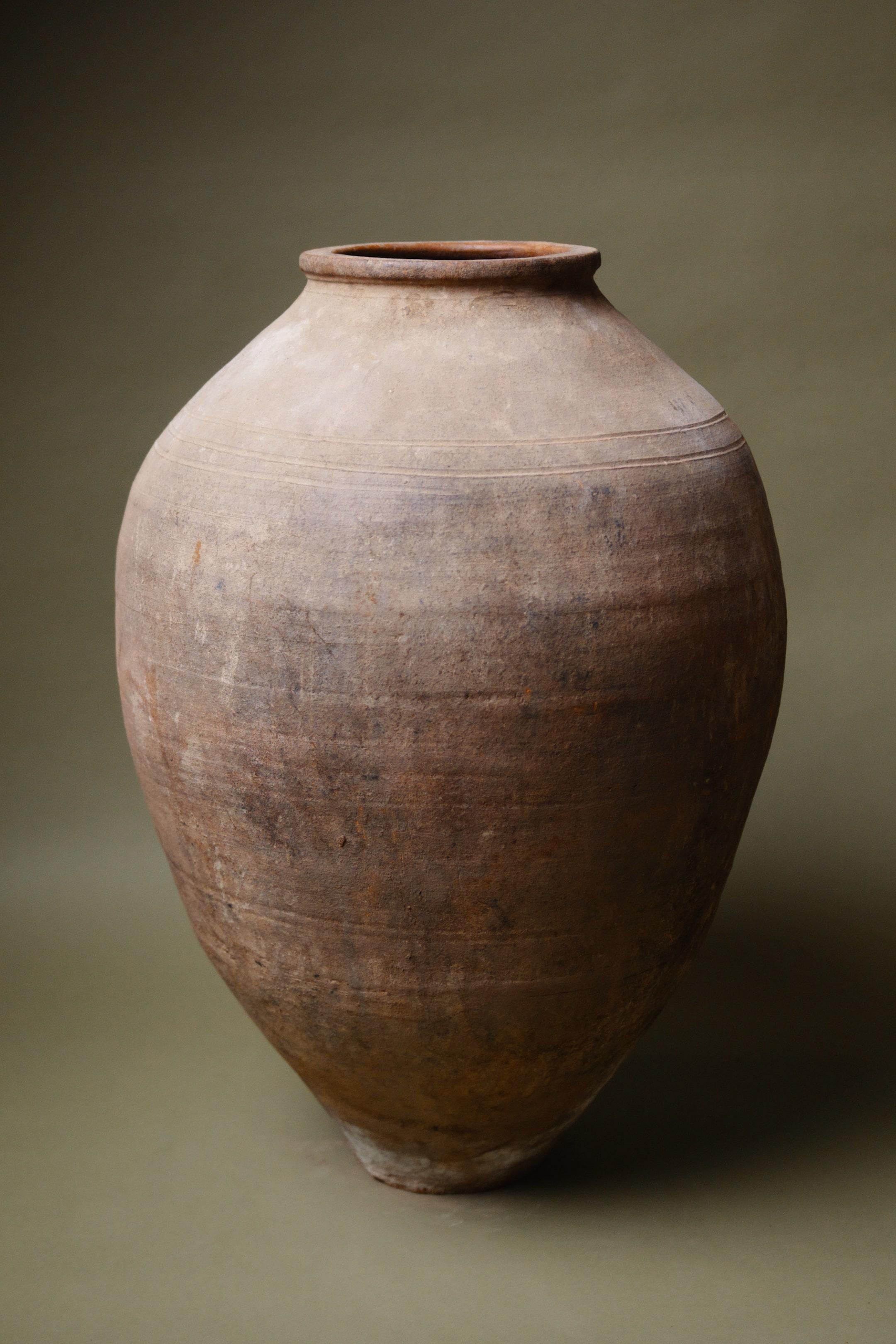 Questo vaso in terracotta anatolica del XX secolo rappresenta la ricca eredità della ceramica turca, realizzata con un'attenzione particolare alla funzionalità e alla durata. La sua forma espansiva e bulbosa era un tempo parte integrante della vita