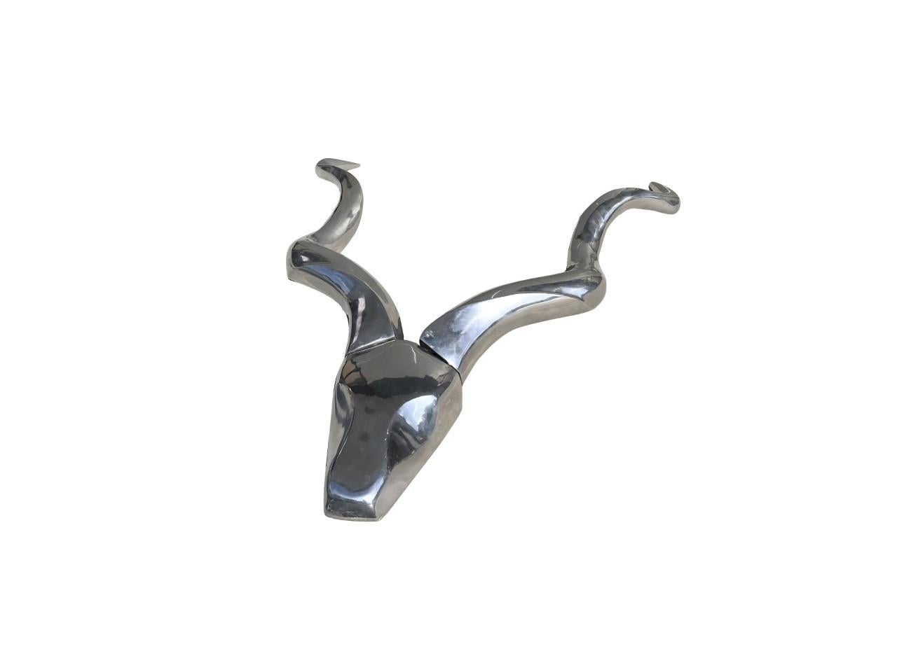 A vintage large Mid-Century Modern American sculpture in polished aluminum, depicting an Antelope head sculpture with wall mount brackets. Designed by Arthur Edward Court. Very important decoration above a fireplace in a contemporary setting, in