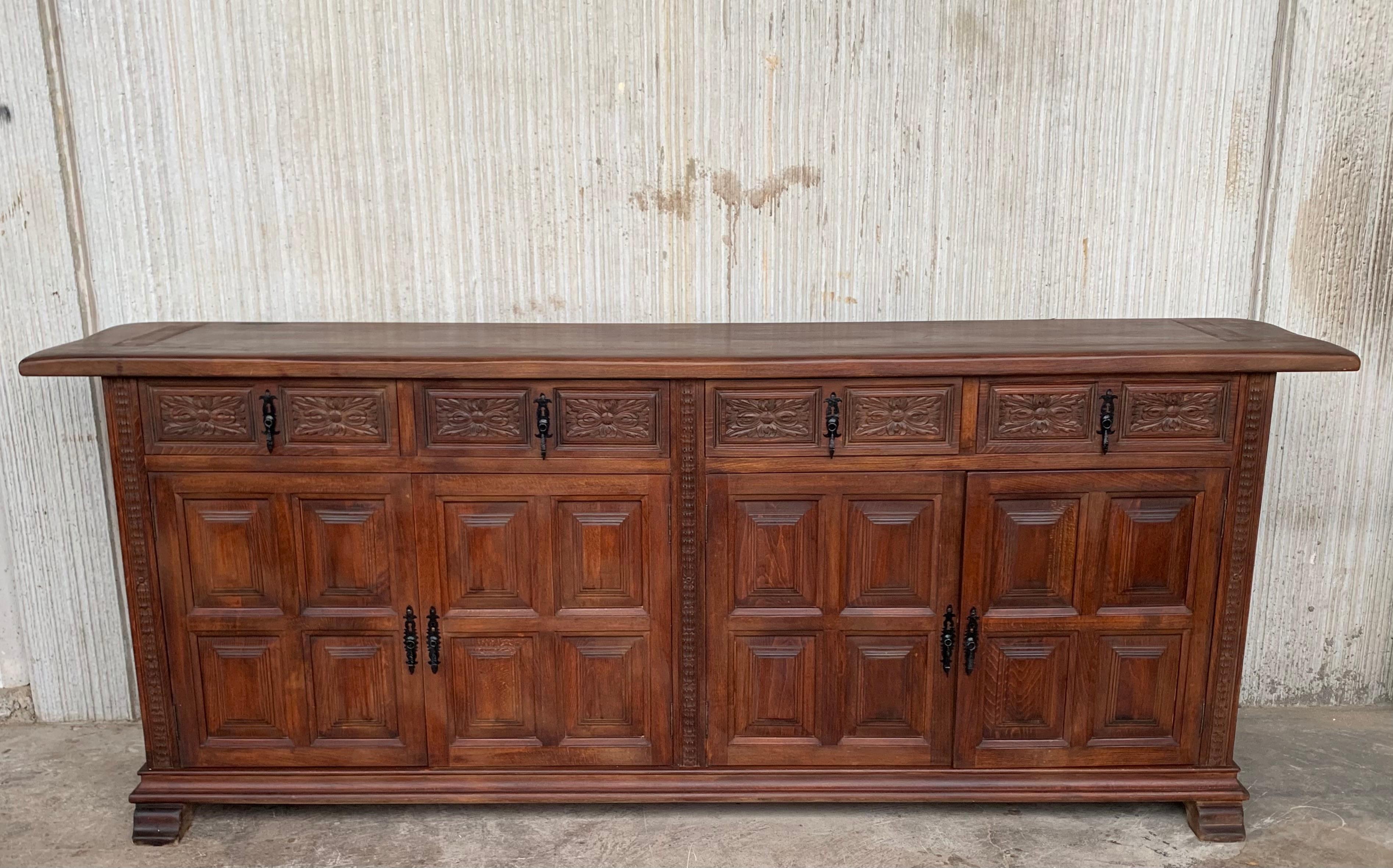 From Northern Spain, constructed of solid walnut, the rectangular top with molded edge atop a conforming case housing four drawers over four doors, the doors paneled with solid walnut, raised on a plinth base. The drawers are hand carved and the