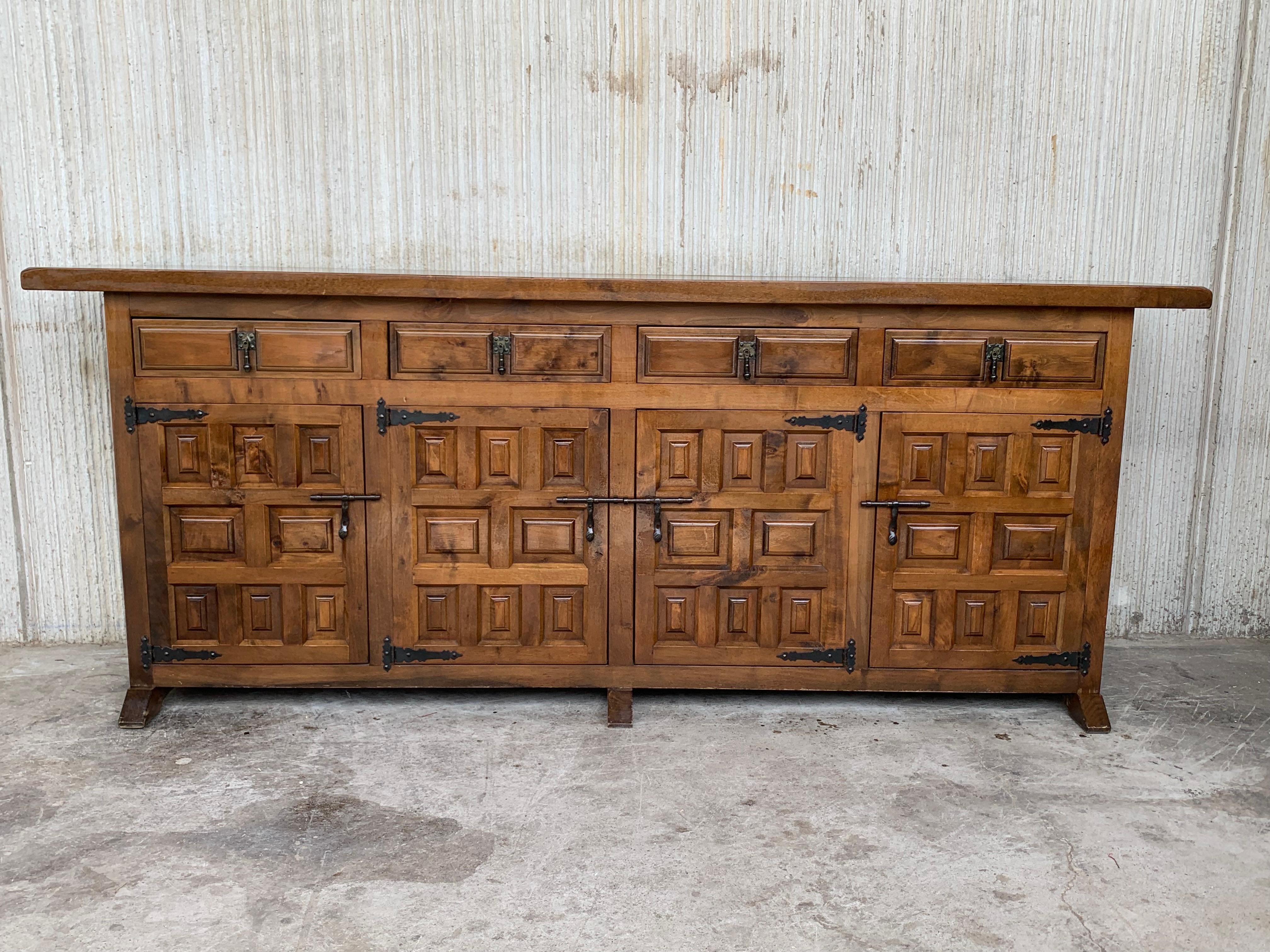 From Northern Spain, constructed of solid walnut, the rectangular top with molded edge atop a conforming case housing four drawers over four doors, the doors paneled with solid walnut, raised on a plinth base. The drawers and doors are hand carved