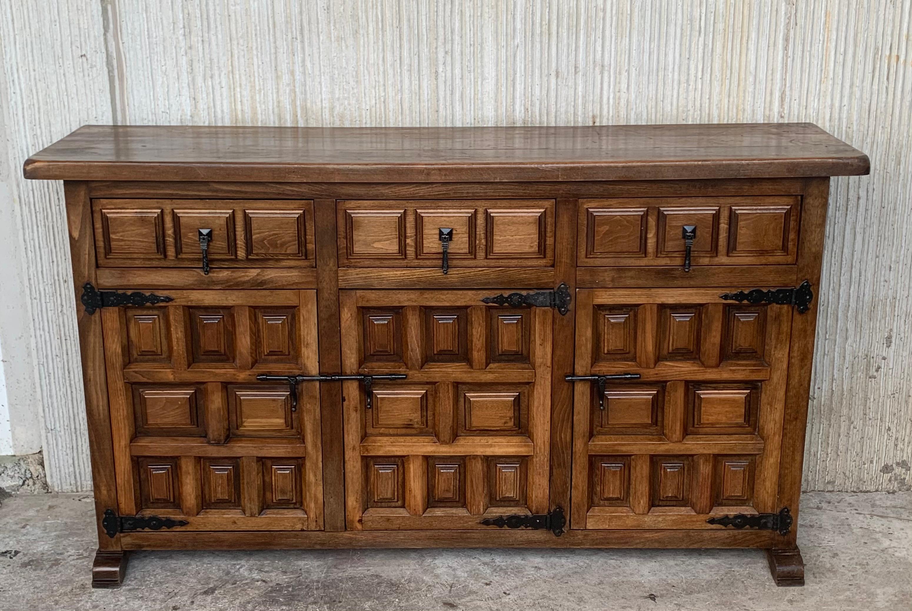 From Northern Spain, constructed of solid walnut, the rectangular top with molded edge atop a conforming case housing three drawers over three doors, the doors paneled with solid walnut, raised on a plinth base. The drawers and doors are hand carved