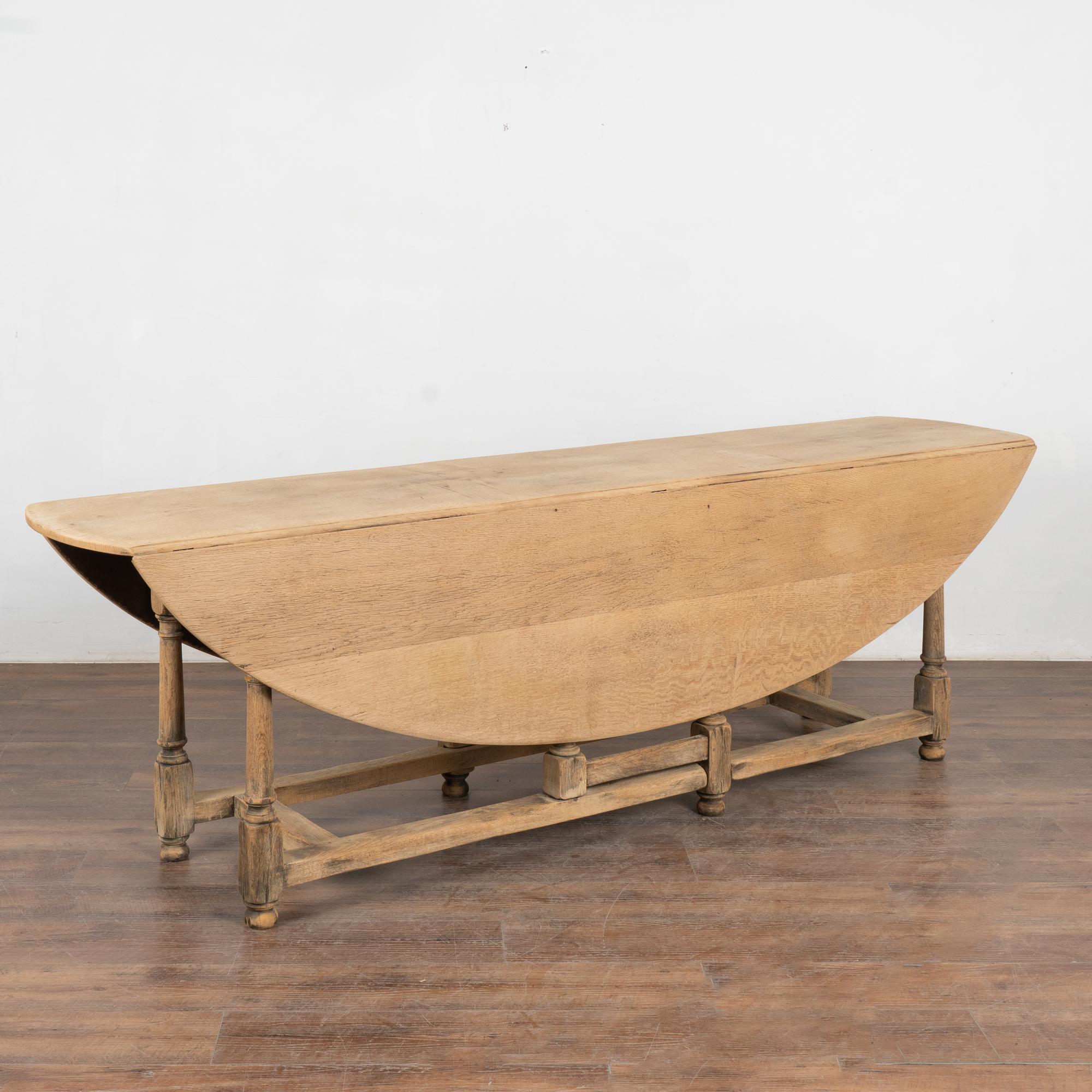 This inviting oak gateleg dining table will serve as a large dining table or long console with drop leaves.
Notice the warm patina of the oak which has been bleached, accenting the soft aged and naturally distressed character of this 8' long dining