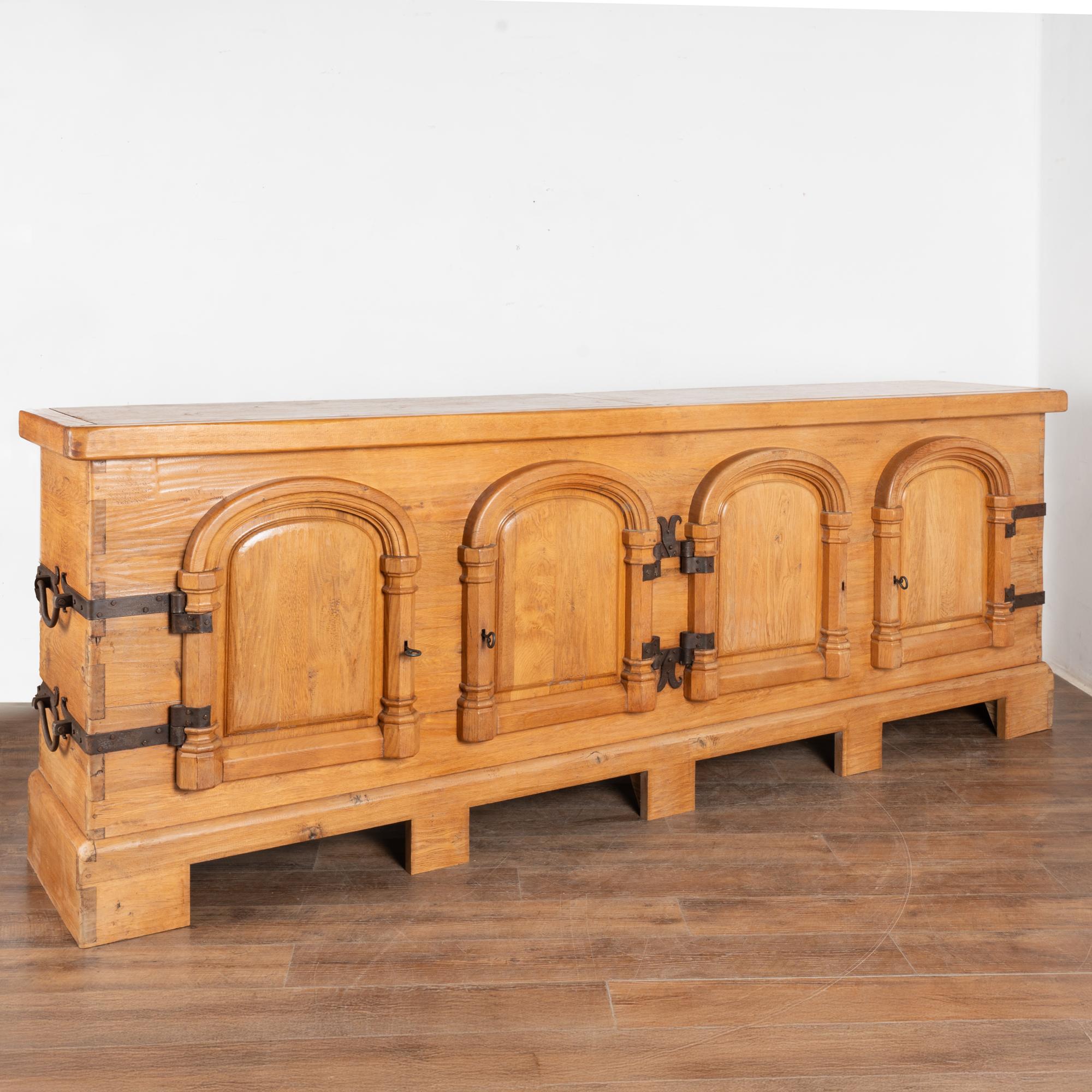 This oak sideboard with original wrought iron hinges and hardware is just under 10' long and has been adapted to serve as a bar as well.
The four front doors open to reveal interior shelves, while the back is open allowing it to store liquor
