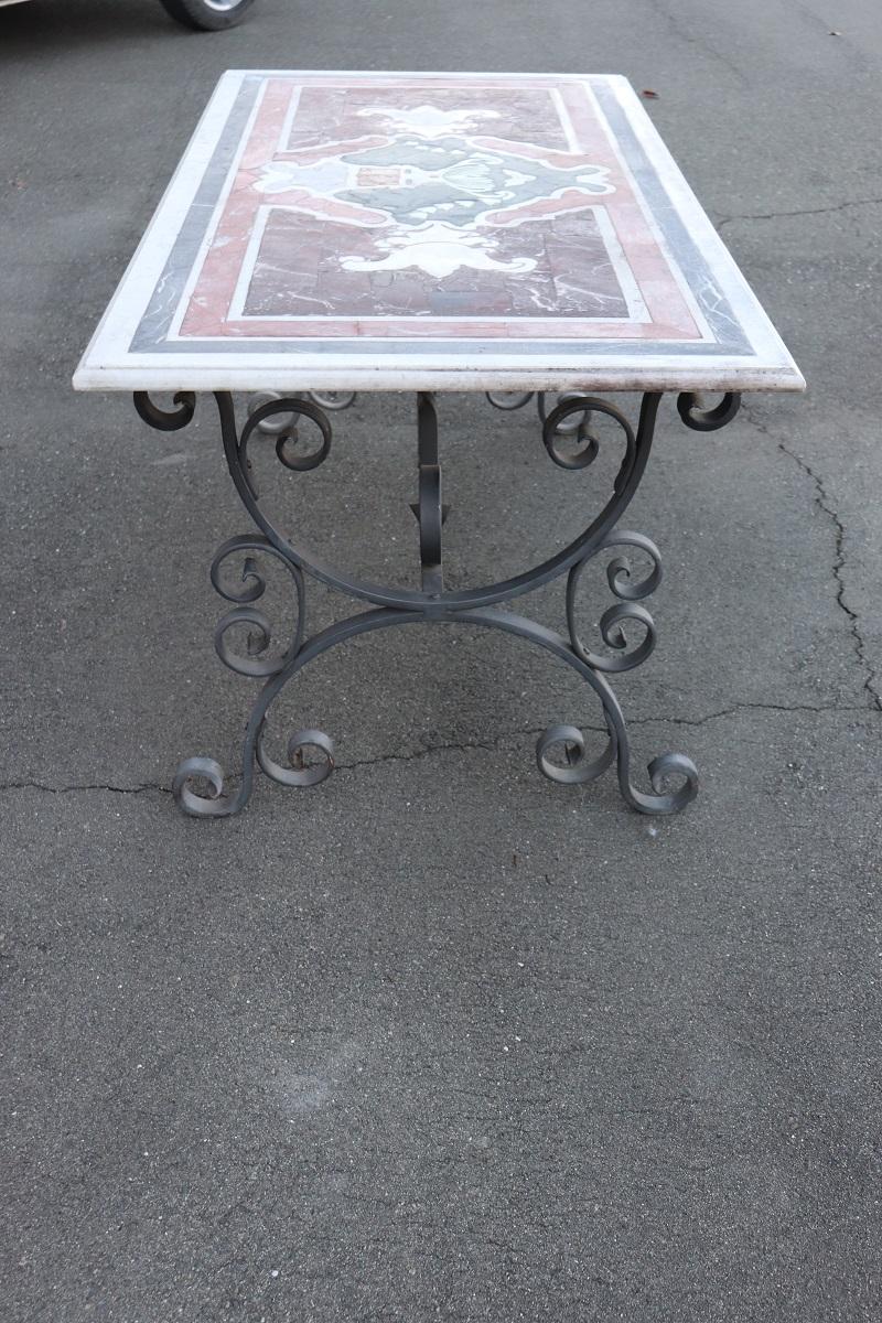 Majestic large rectangular garden or patio table. Made with iron base and marble top. Characterized by a rich iron decoration with scrolls. The high quality marble top with a classic decoration made with inlay using various fine marbles of many