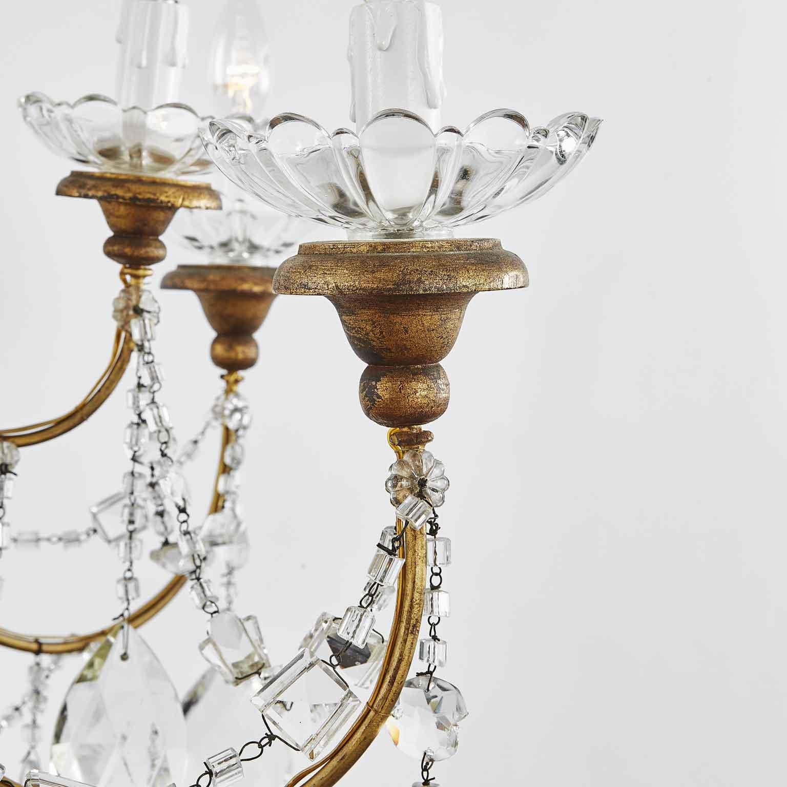 A stunning 1910s Italian  two-tiered 12-light gilt-iron and crystal beaded chandelier. The chandelier’s gilt-iron frame is all hand beaded and features a beautiful time-worn patina. Each of the chandelier’s 12 glass bobeche rest on giltwood mounts.