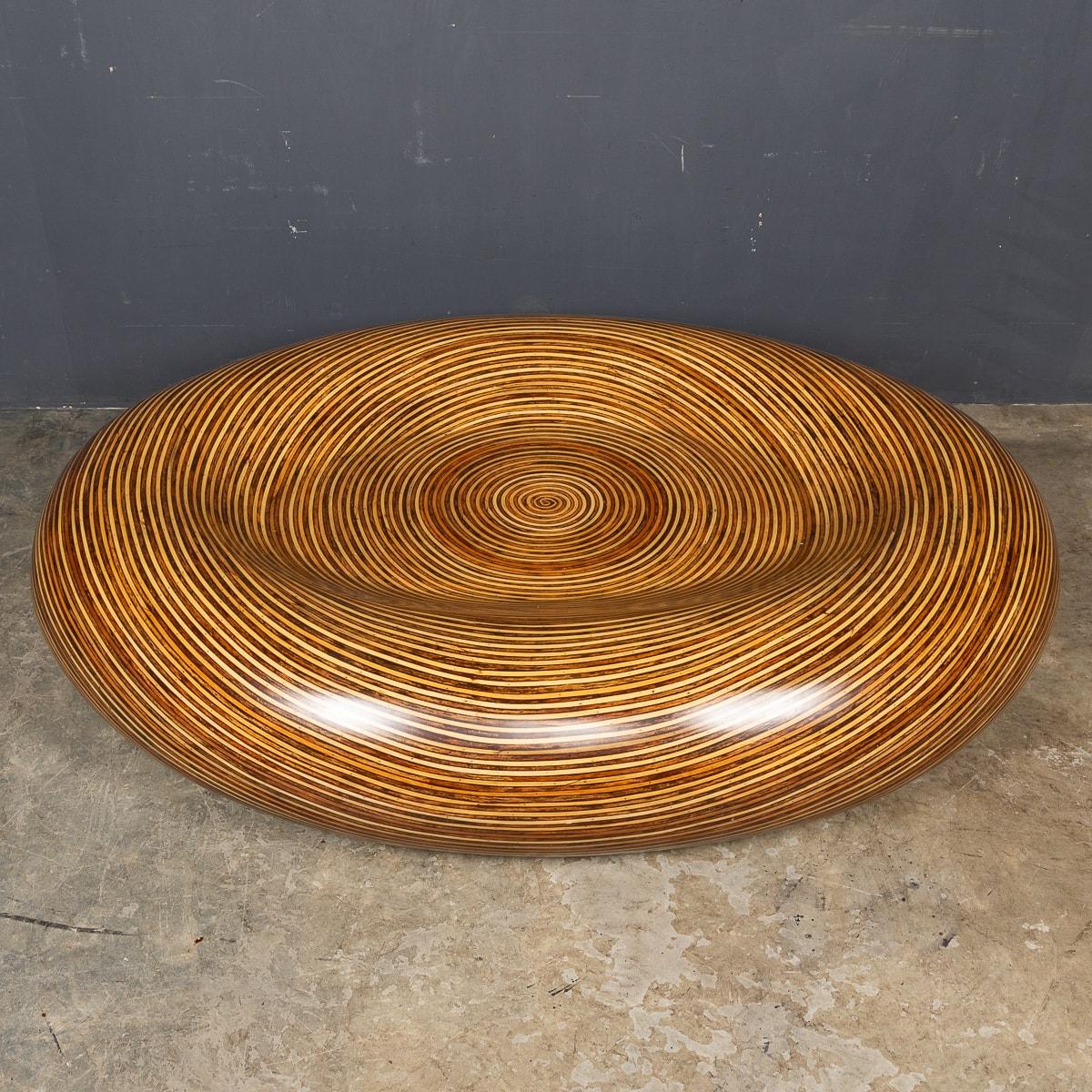 A superb 20thC fibreglass table seamlessly moulded into a captivating round form, with a layered wood-effect pattern that spans its entire surface. This generously sized table boasts smooth edges, enveloping a flat central area—ideal for a serving