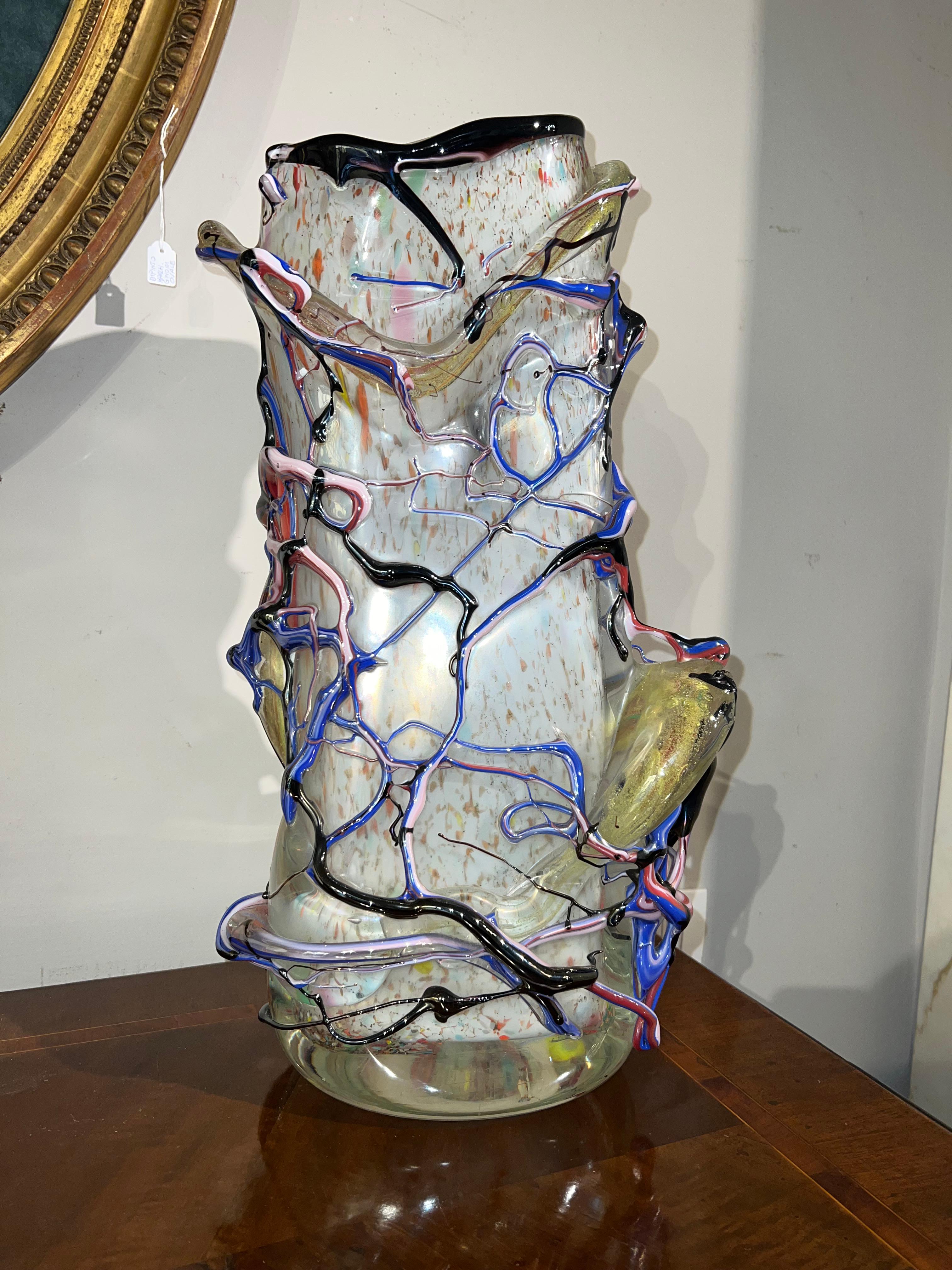 Magnifique et unique vase en verre de Murano. Ce vase a été réalisé avec talent, en utilisant du verre laiteux pour l'intérieur et une structure de branches filiformes polychromes pour l'extérieur. Les décorations en verre coloré polychrome