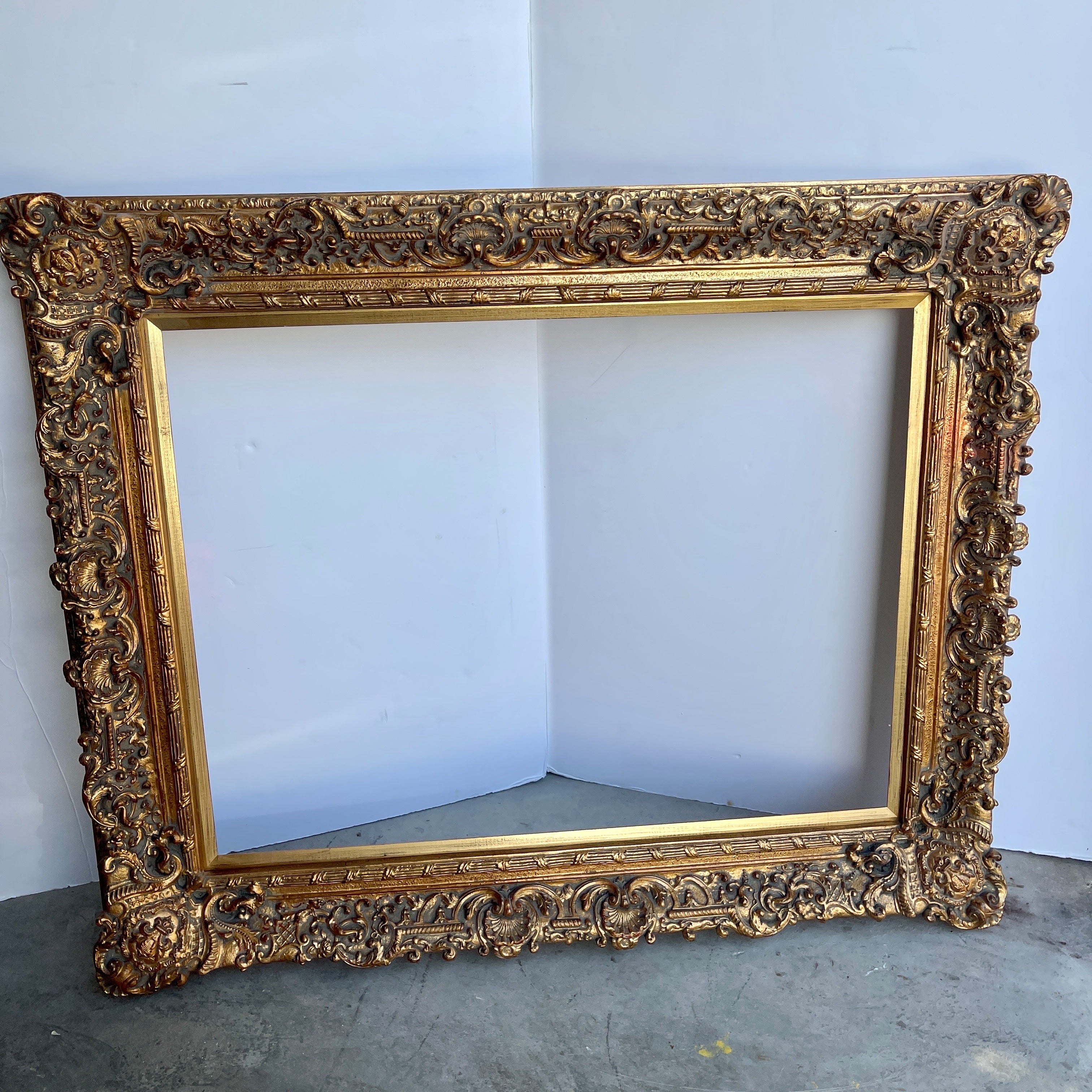 Large Ornate French Rococo Style Carved Ornate Gilt Wood Frame.

This gorgeous hand-crafted frame has lots of charming details including fleur de lis in the corners, shell motifs as well as other fantastic features. This substantial piece could be