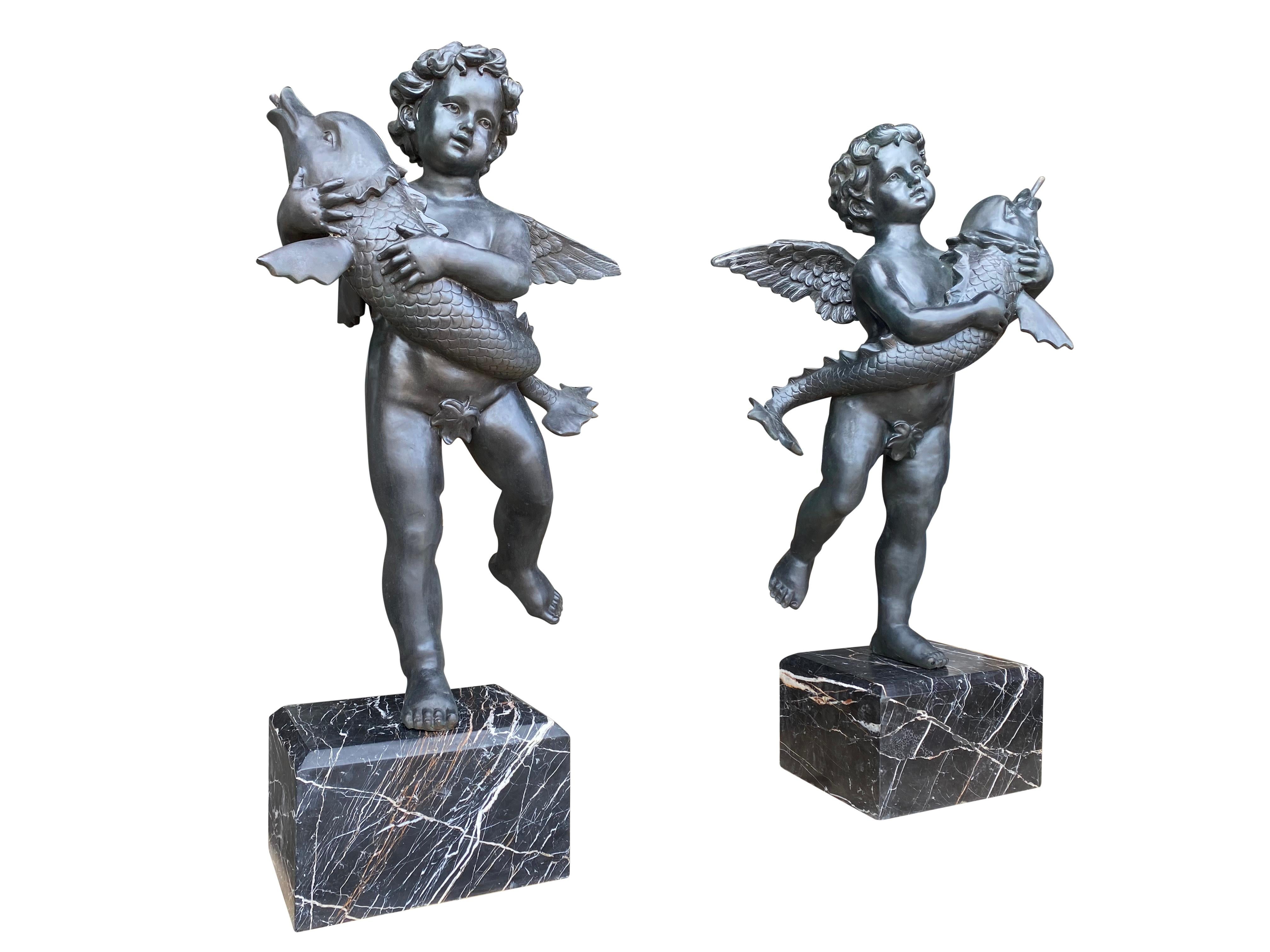 A large impressive pair of 20th century bronze Cherub fountains with fish. Situated on Verdi Antico marble bases. This pair are fully functional working fountains, perfect for garden use and ponds.