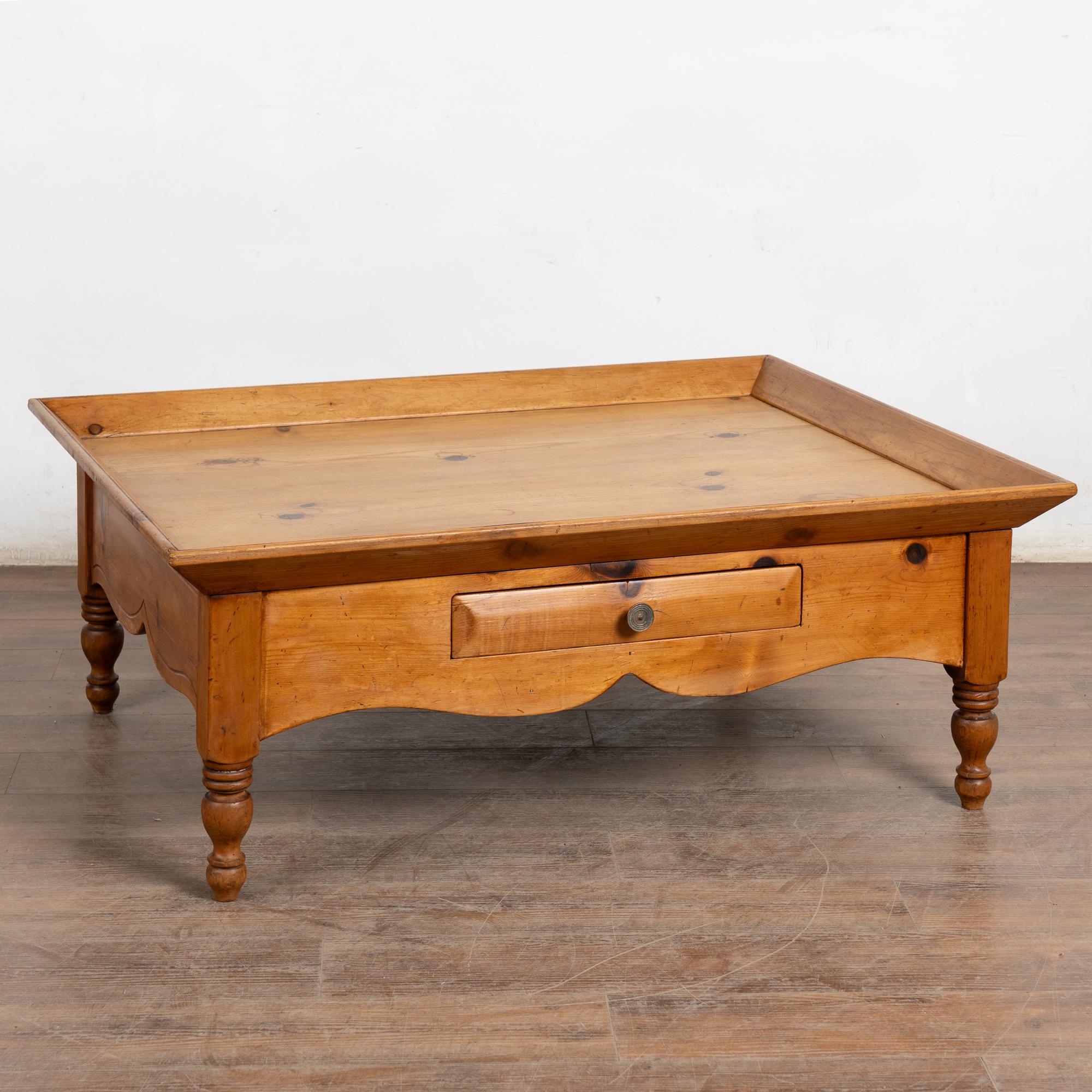 Large pine coffee table with raised edge and two drawers fitted with brass pulls. Scalloped skirt, turned legs, and warm pine tone add to its charm.
Restored, strong, and stable; a simple yet inviting table ideal for casual entertaining, games, or