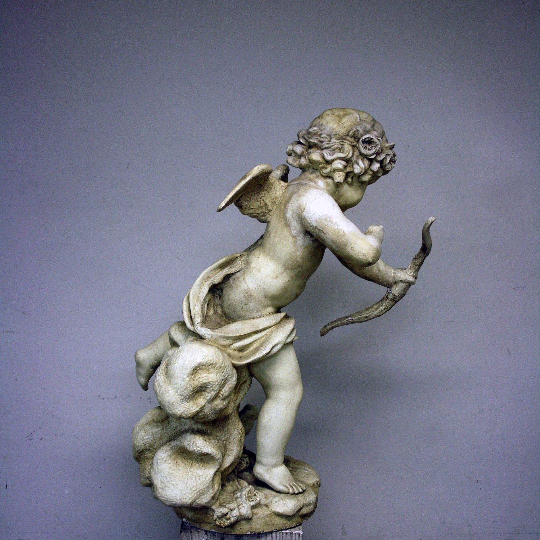A 20th century large plaster figure of Cupid sitting upon a cloud aiming taking aim with his bow.

Wear consistent with age, old repair to wings.