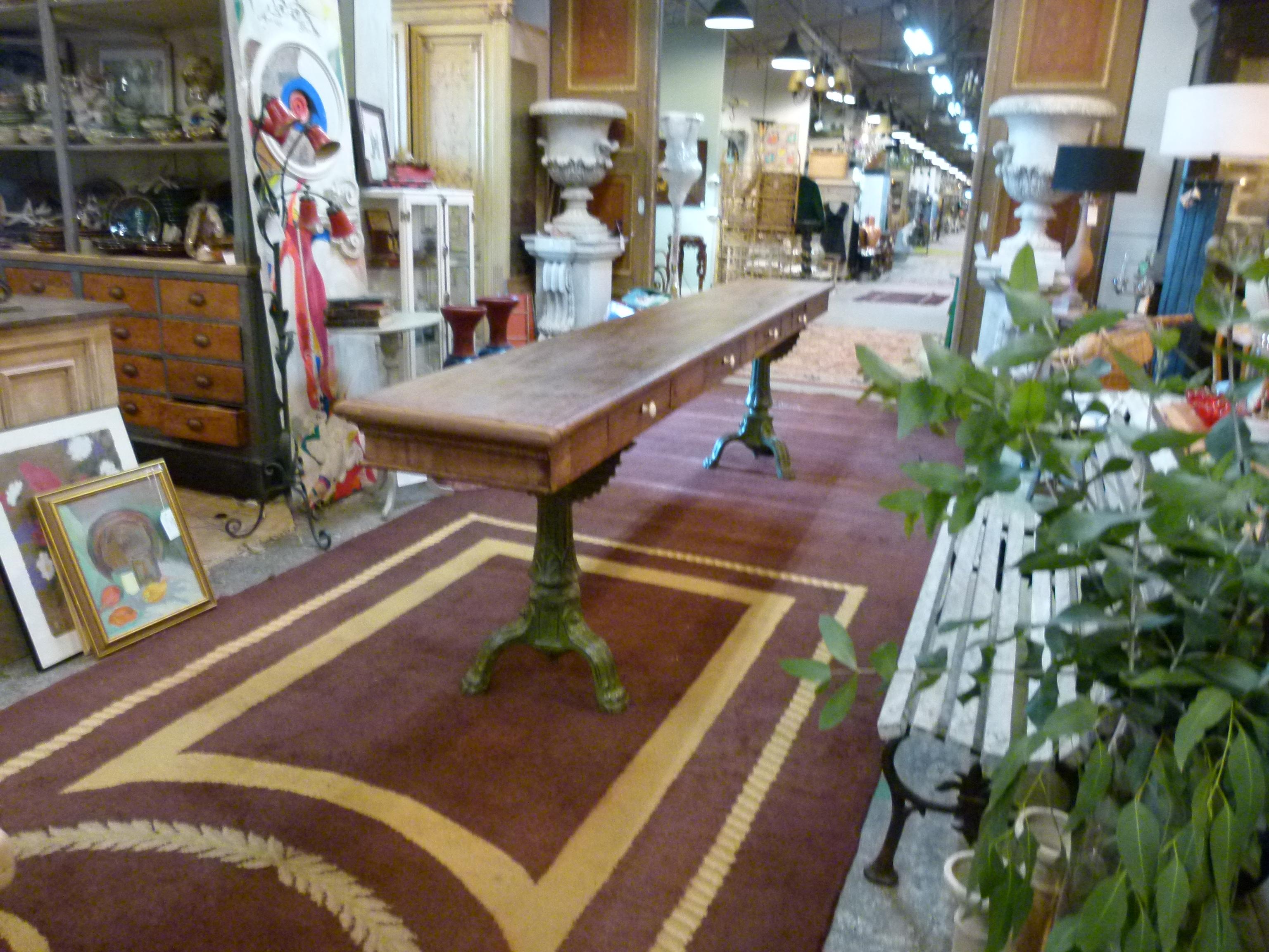 Typical early 20th century work table from a textile store. Made of hard wood and cast iron feet. It contains four drawers with porcelain knob.
   