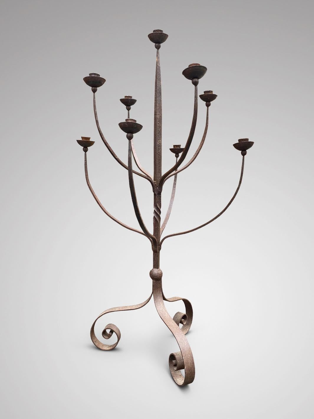 A large 20th century wrought iron 9 branch floor standing candelabra, on three scroll supports. Very decorative item.

The dimensions are:
Height: 163cm (64.2in)
Diameter: 92cm (36.2in)

This wrought iron candelabra is in good antique condition