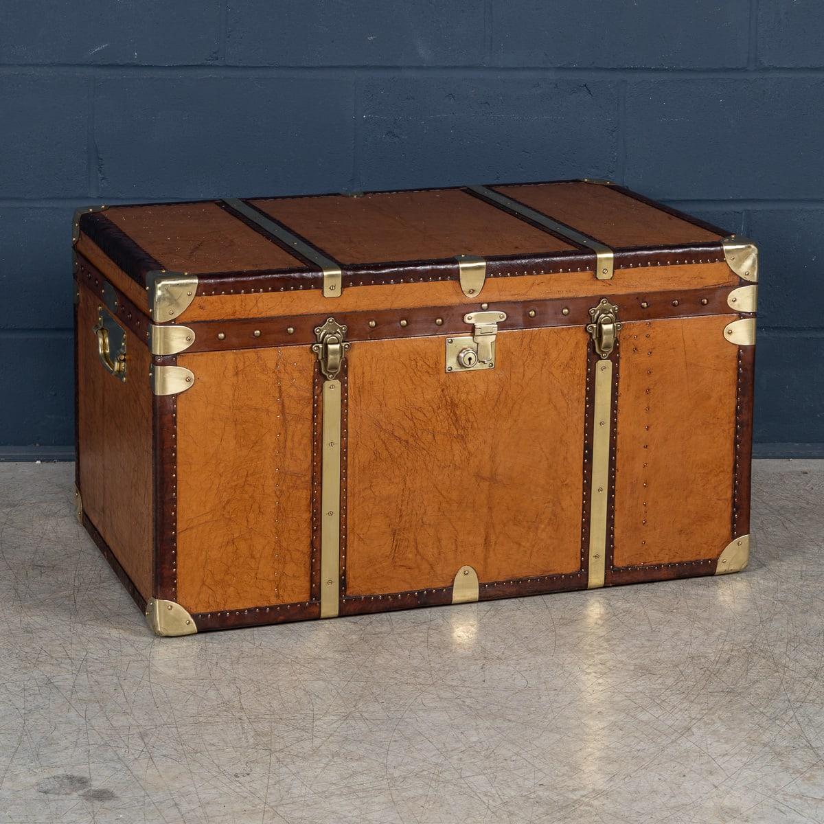 A leather-clad Army and Navy style trunk, crafted in England in the late 20th century, exuding rugged sophistication and timeless appeal. Inspired by traditional military campaign trunks, it features sturdy leather exteriors with robust metal
