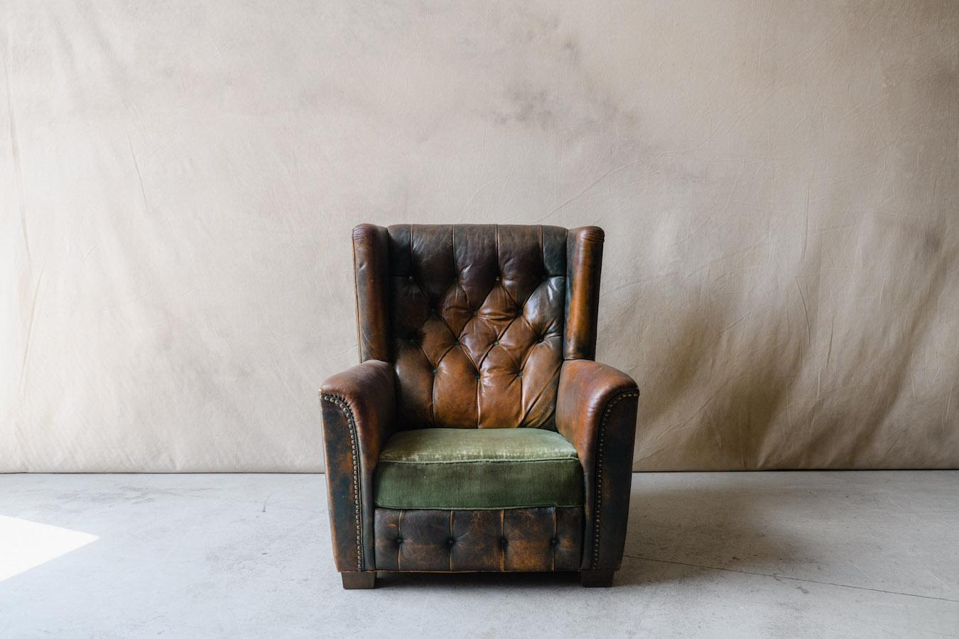 20th Century leather wingback chair from Denmark, Circa 1940. Superb large model with original green leather and velvet upholstery. Amazing wear and patina on the leather, with large nail heads at seams. 

We have kept this one for ourselves for the