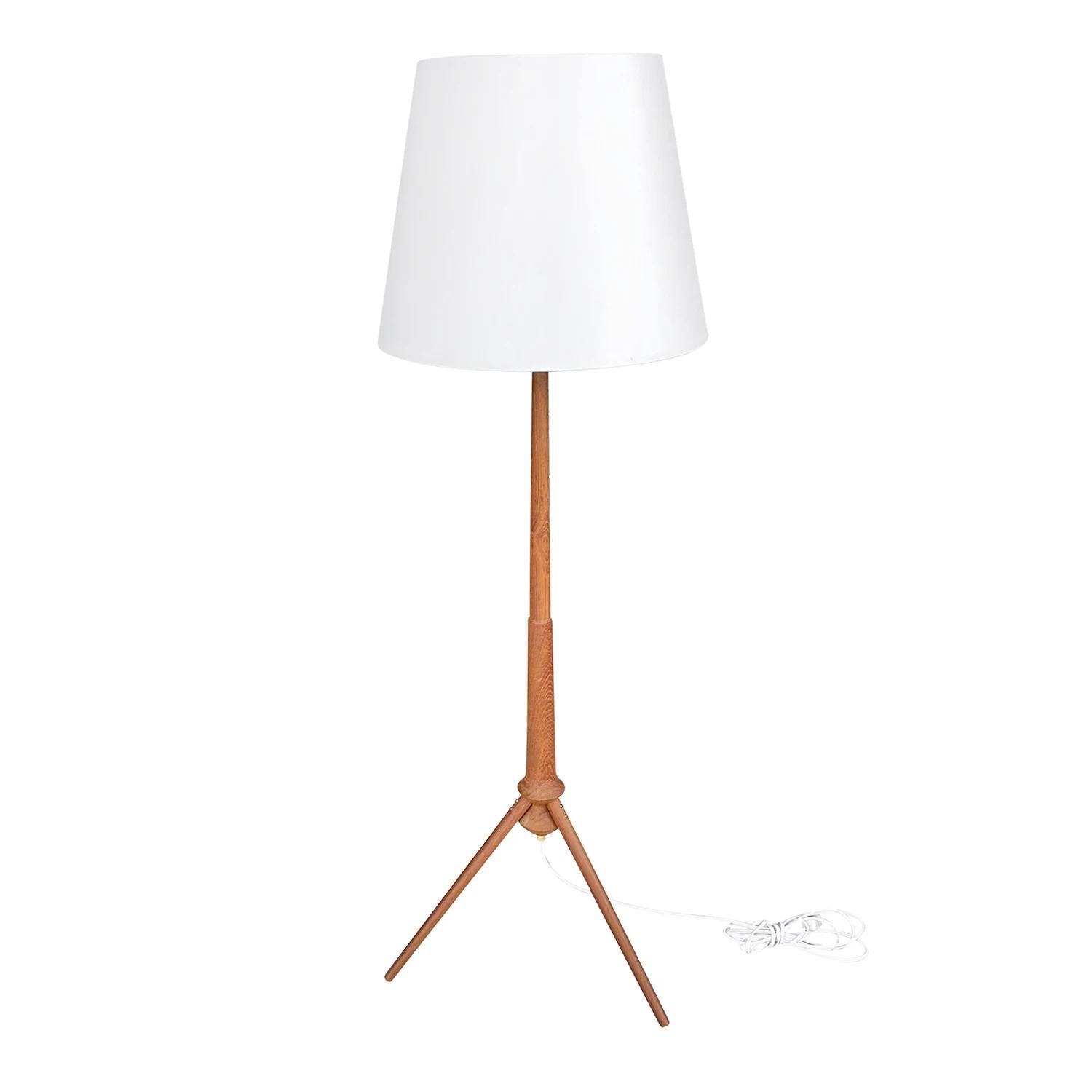 A vintage Mid-Century Modern Danish floor lamp made of hand crafted Teakwood, in good condition. The Scandinavian light is composed with a new white round shade, standing on three curved legs. The wires have been renewed. Wear consistent with age