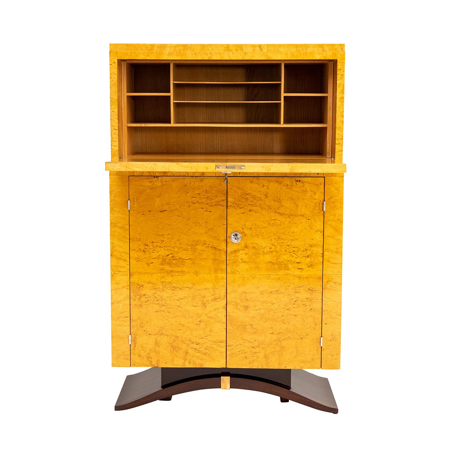 A detailed, vintage Art Deco French secretaire made of hand crafted polished, partly veneered Birchwood and Burlwood, in good condition. The medium sized cabinet is composed with two doors and a writing flap, consisting its original chrome hardware