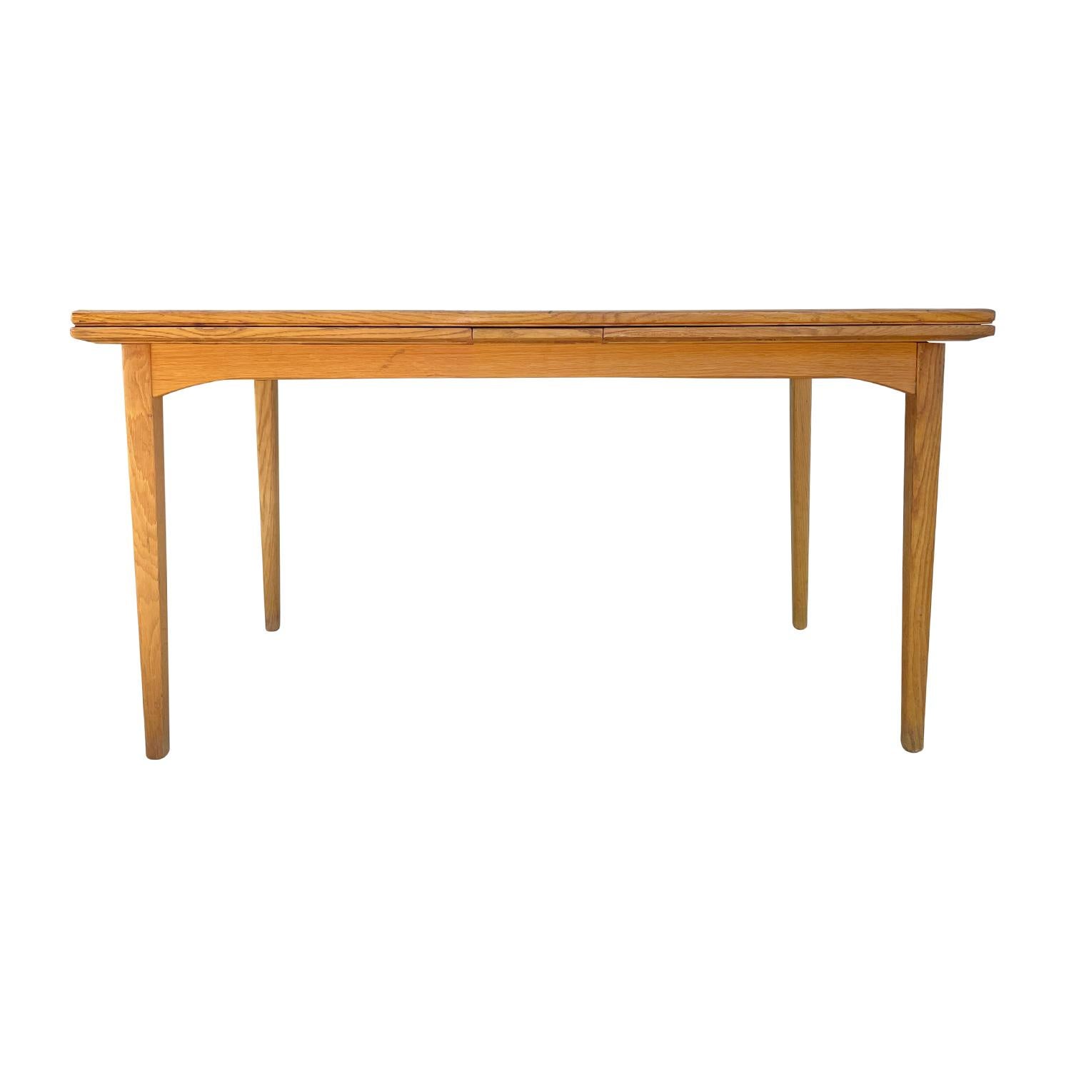 A light-brown, vintage Mid-Century Modern Swedish extendable dining table made of hand carafted Walnut with two pullout leaves which are stored underneath, designed by Carl Malmsten in good condition. The Scandinavian rectangular table is standing