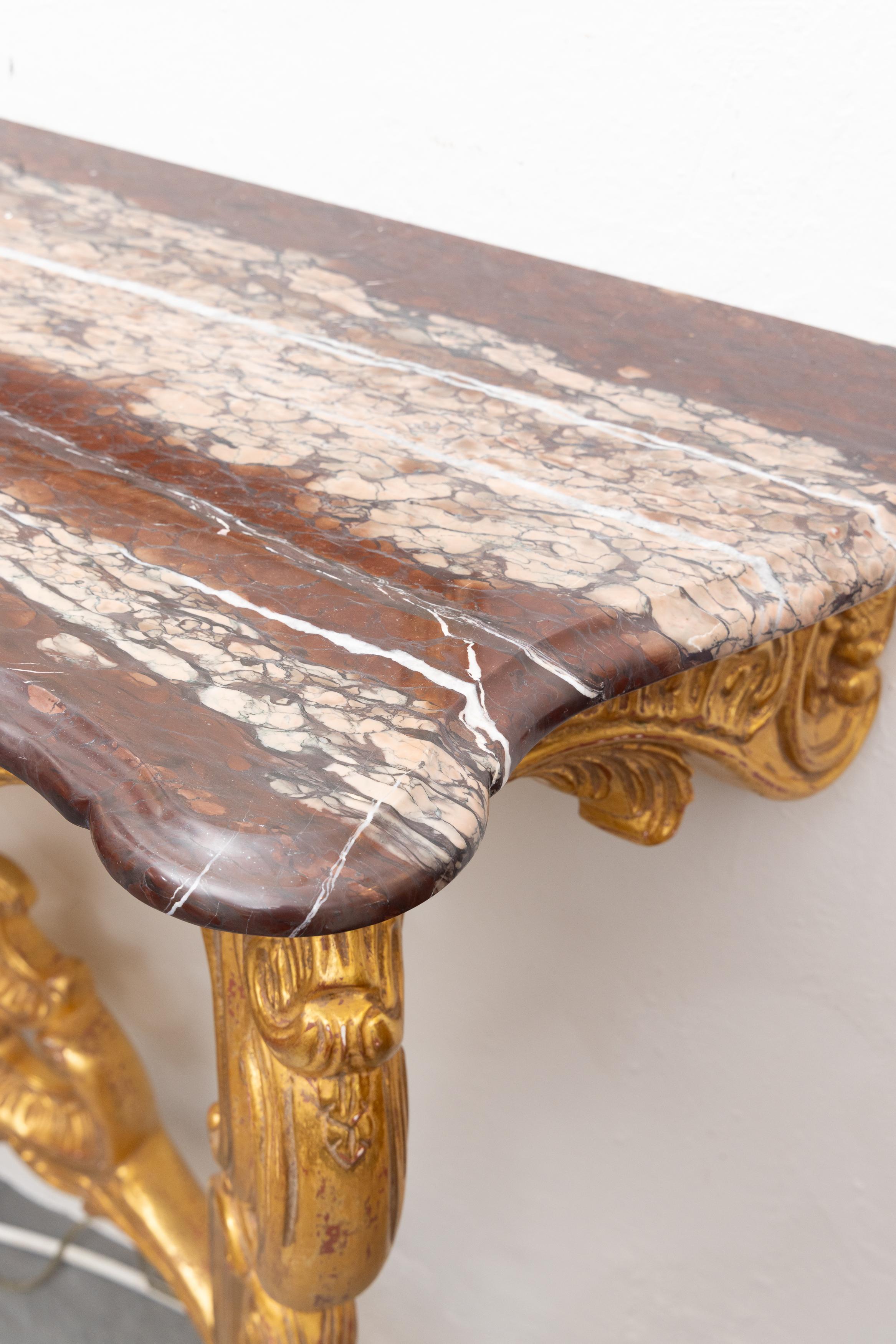 This is one of a pair of early 20th century French Louis XV style consoles.  The rouge marble top is over a carved, pierced frieze,  flanked by carved cabriole legs joined by a pierced stretcher.