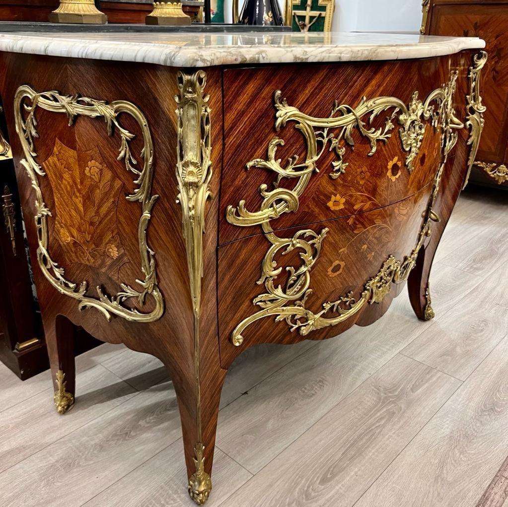 We present you this beautiful Louis XV-style bombe chest of drawers with two drawers and no crossbar from the early 20th century. It is adorned with rich gilded bronze decorations representing foliage motifs and soft shapes on the front and sides.