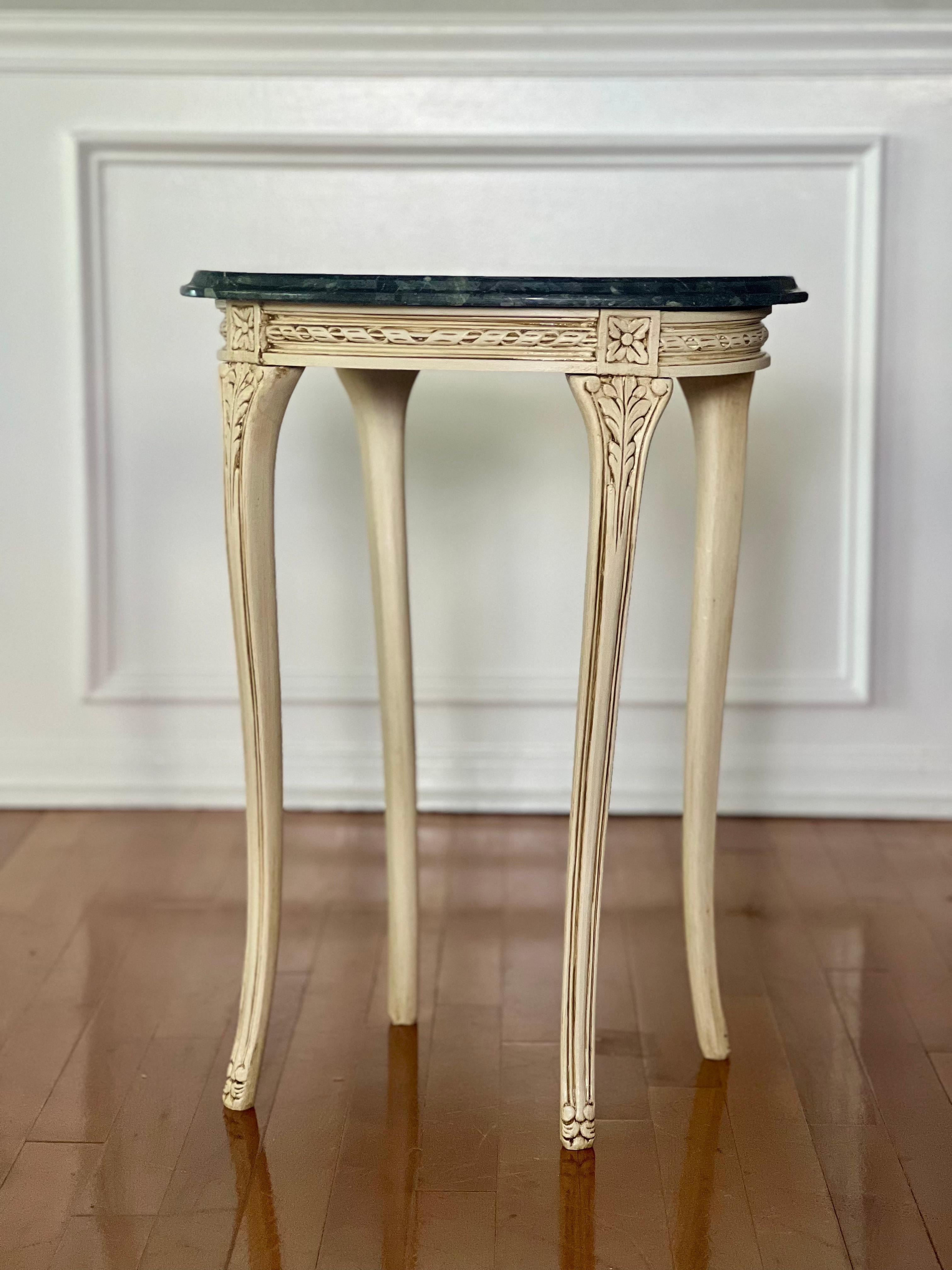 Table d'appoint vintage du 20ème siècle de style Louis XV peint et sculpté avec un plateau en marbre vert foncé. Elle est peinte dans une couleur bisque et sculptée dans un design français classique sur d'élégants pieds cabriole. Le plateau de