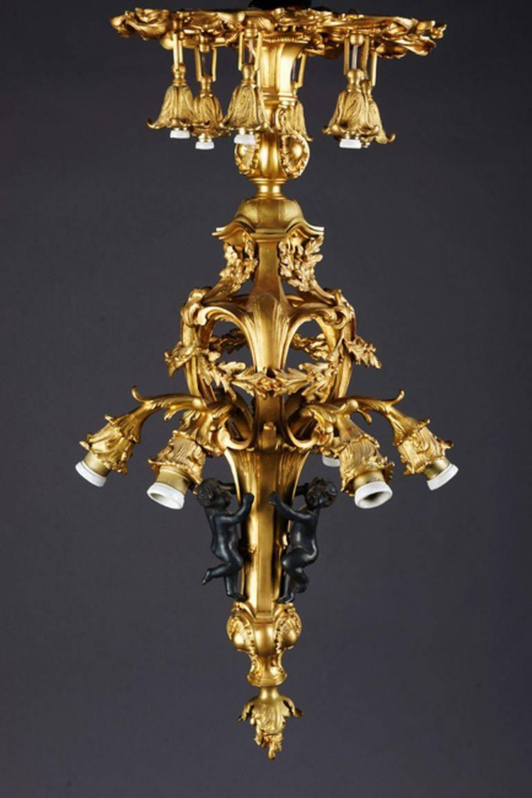 Prince Louis XV-style French chandelier.
Finely chased and gilded bronze. Twelfth. Volute-cover ring for elongated, articulated, in the middle basket-shaped shank with pin end. In each case six suspended electr. Flames on two levels. Akanthus,