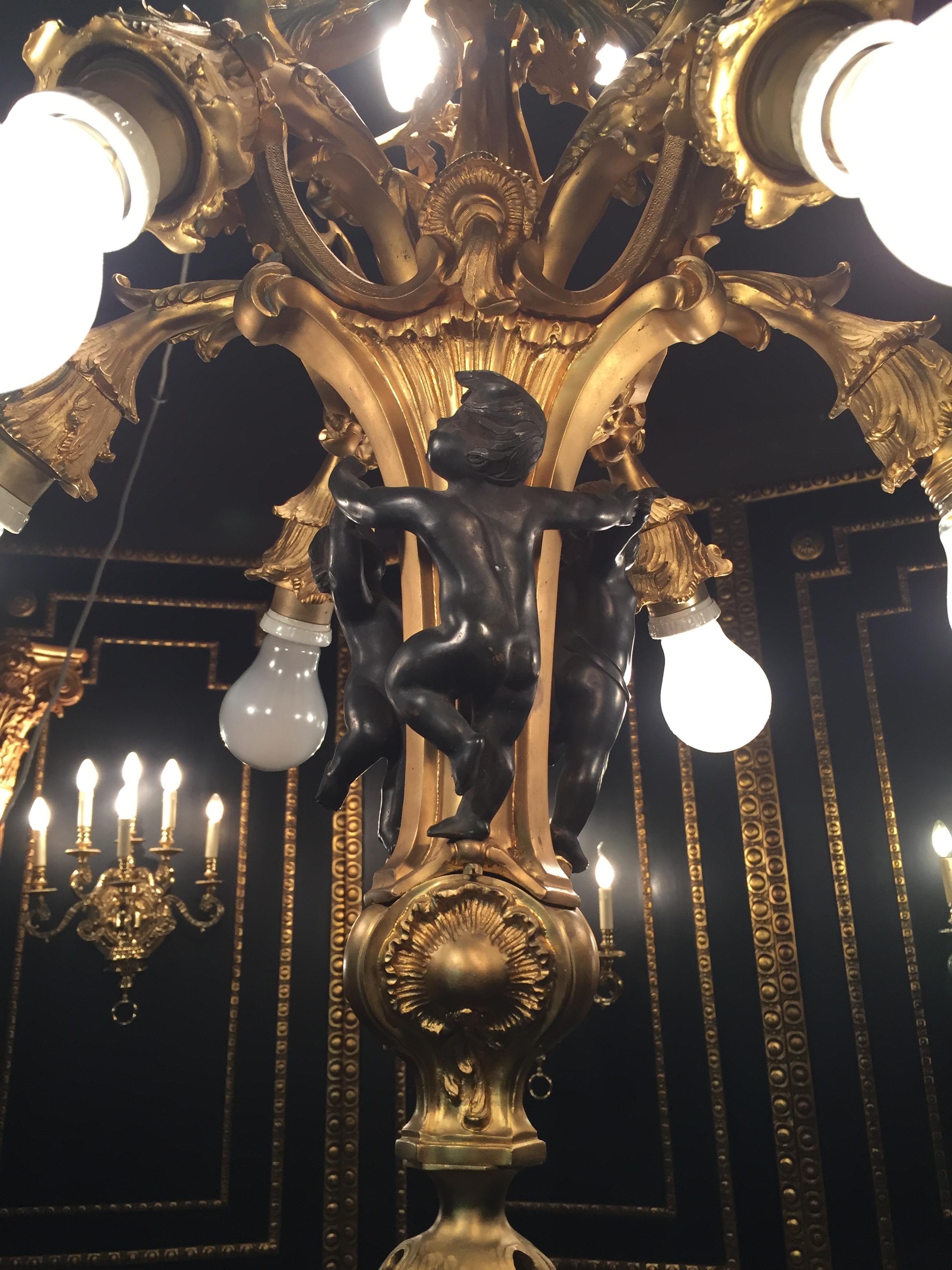 Prince Louis XV-style French chandelier. Finely chased and gilded bronze. Twelfth. Volute-cover ring for elongated, articulated, in the middle basket-shaped shank with pin end. In each case six suspended electro. Flames on two levels. Akanthus,