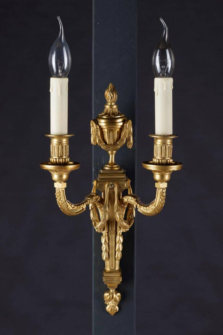 Applique Louis XVI in the style of Jean Louis Prieur 1732-1795.
Matte and gilded bronze. Narrow, profiled wall panel with large attachment in the form of a handle vase and two curved light arms with vase-shaped grommets and round drip plates.