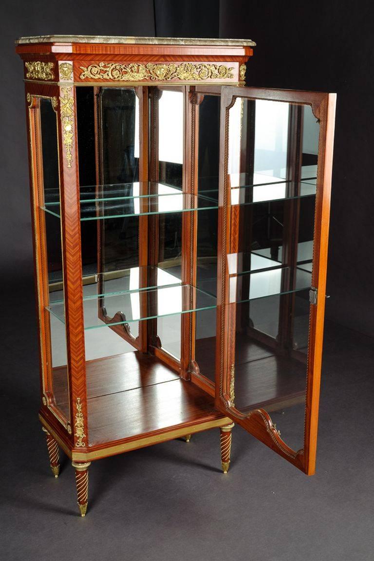 Exclusiva vitrina francesa de estilo Luis XVI.
Bronce finamente grabado y moldeado. Madera maciza de haya. Cuerpo acristalado de tres lados, de un solo cajón, sobre patas cónicas. Plato de mármol moteado enmarcado de perfil. En el anverso, esquinas