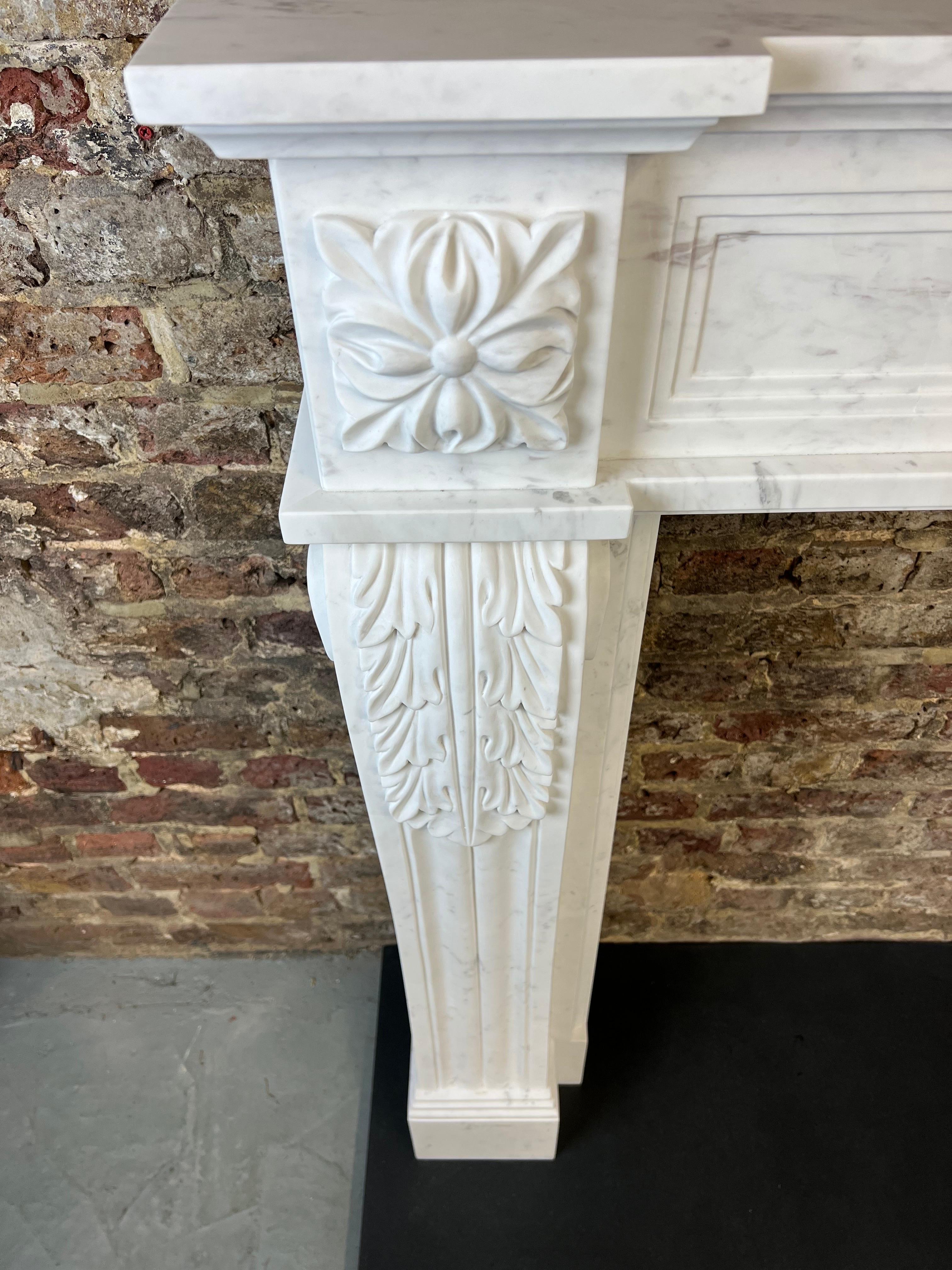 20th Century Louis XVI style antique marble fireplace mantlepiece.
Hand Carved in quality Italian Statuary (white) marble with a honed surface finish. Carved with decorative foliage on each jamb, centre tableau and capital, together with a recessed