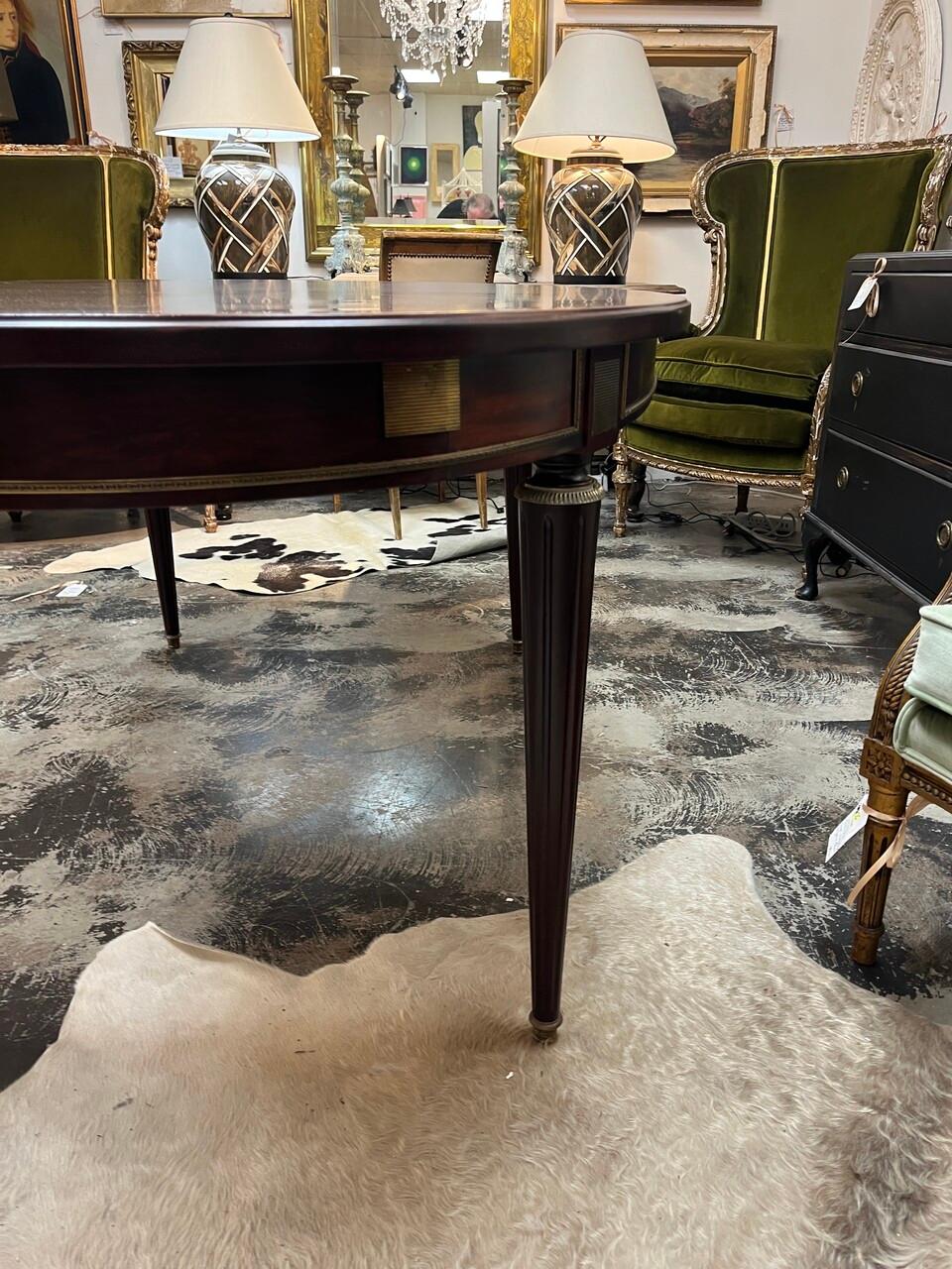 20th Century Louis XVI Style Oval Dining Table with beautiful flame mahogany top and bronze sabots leading to fluted, tapered legs.