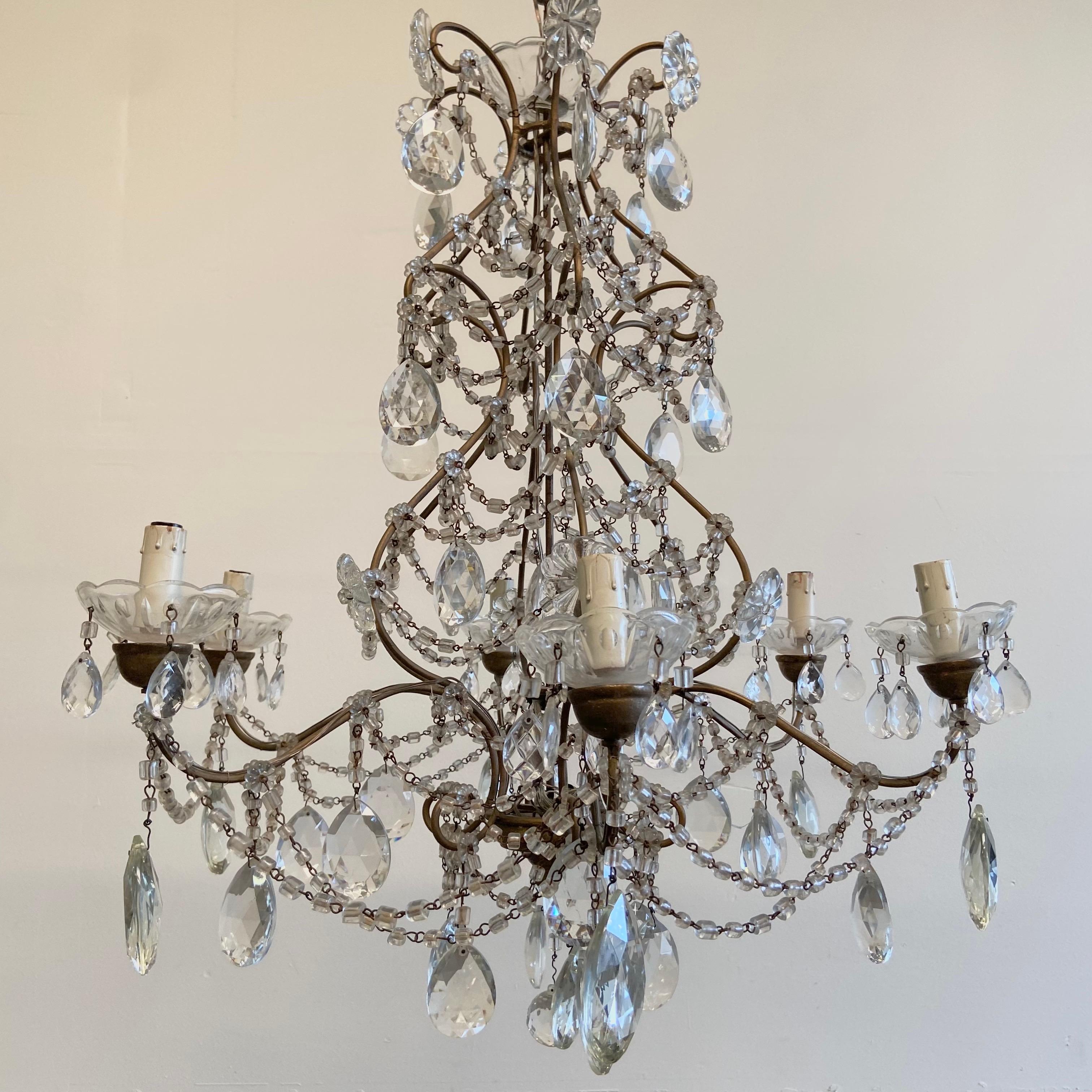 6 light chandelier 25” x 25” x 30”h
Bronze frame, with wood bobeche and glass cups.
Draped in hand cut macaroni beads, and cut glass prisms.
Wood is finished in an aged gilt, and has a dark bronze looking finish.
There is not a ceiling canopy,