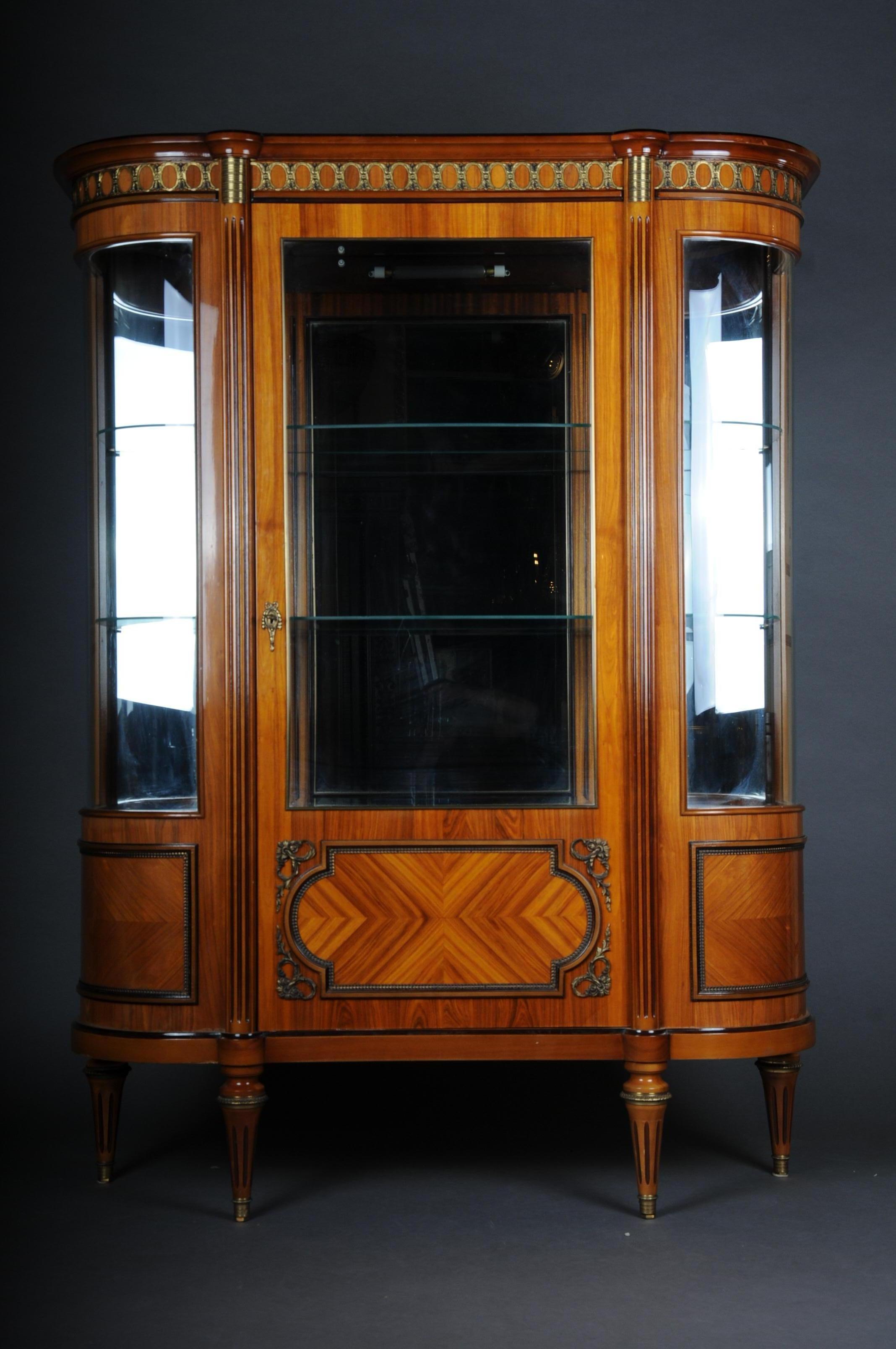 20th century magnificent French Louis XVI style display cabinet

Bois-Satiné veneer, all-round surface-covering mirror veneer on wood. Upright rectangular and rounded, glazed on three sides, body on conical legs. Lockable with one door. The
