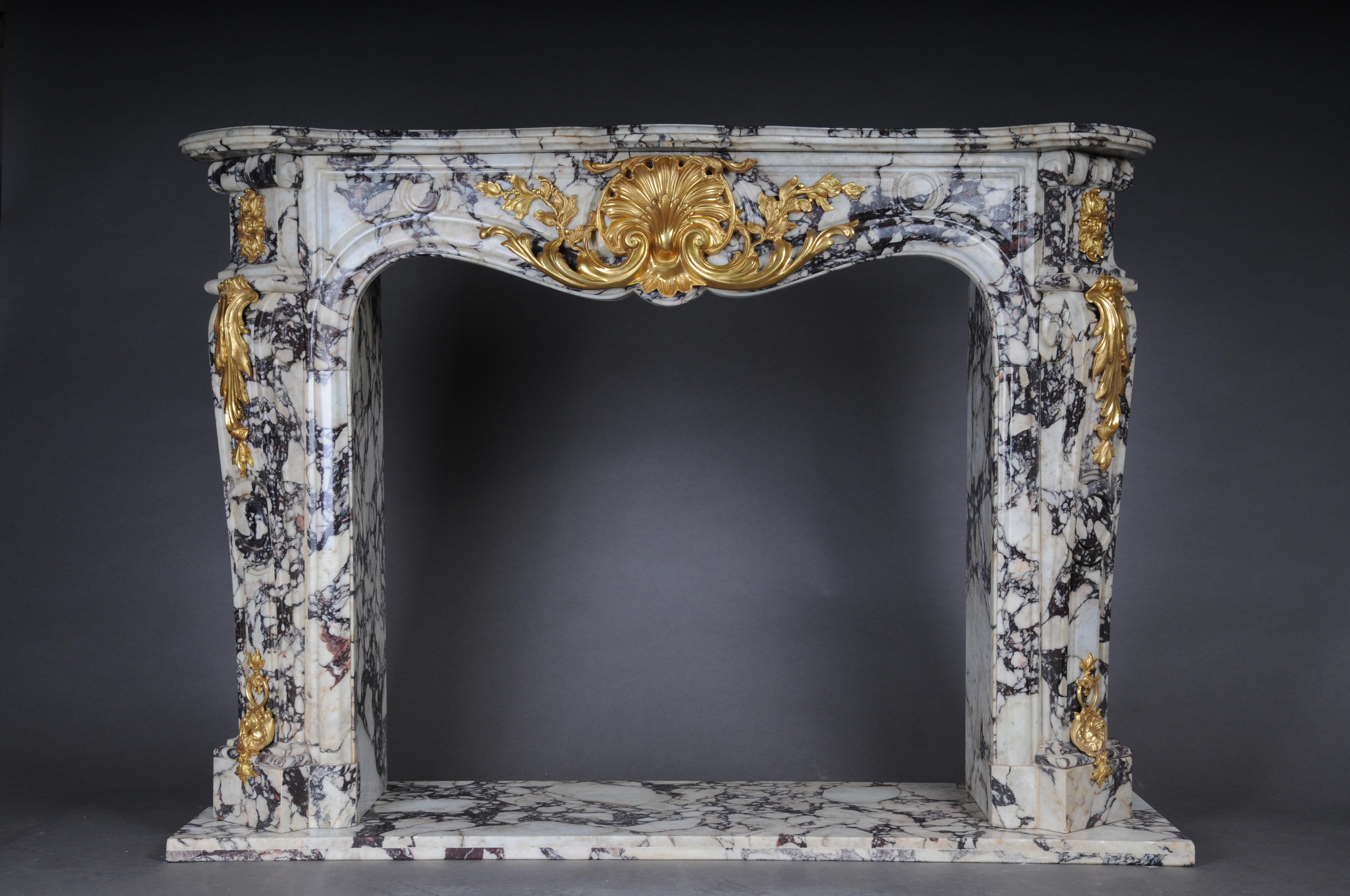 Magnificent French marble fireplace with gilded bronze.

Multiple and elegantly curved white marble with black mottle. Tall and very elegant structure in classic French style, adorned/covered with finely engraved and gilded bronze applications. In