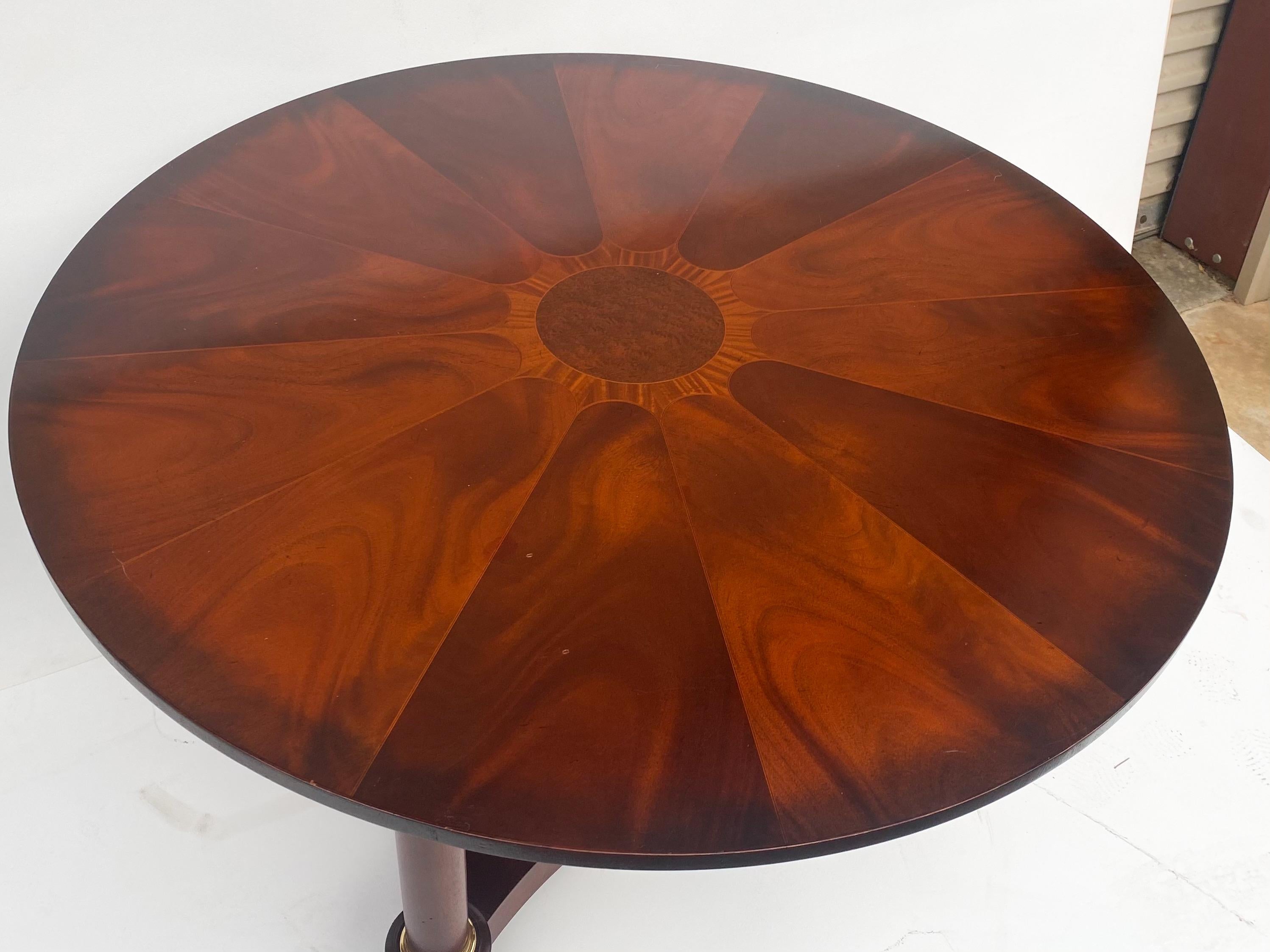 This is a wonderful mahogany and satinwood inlaid center table with empire styling by Baker Furniture Company. The tripod base has base is brass capped and flame mahogany. It is marked and in very good condition.