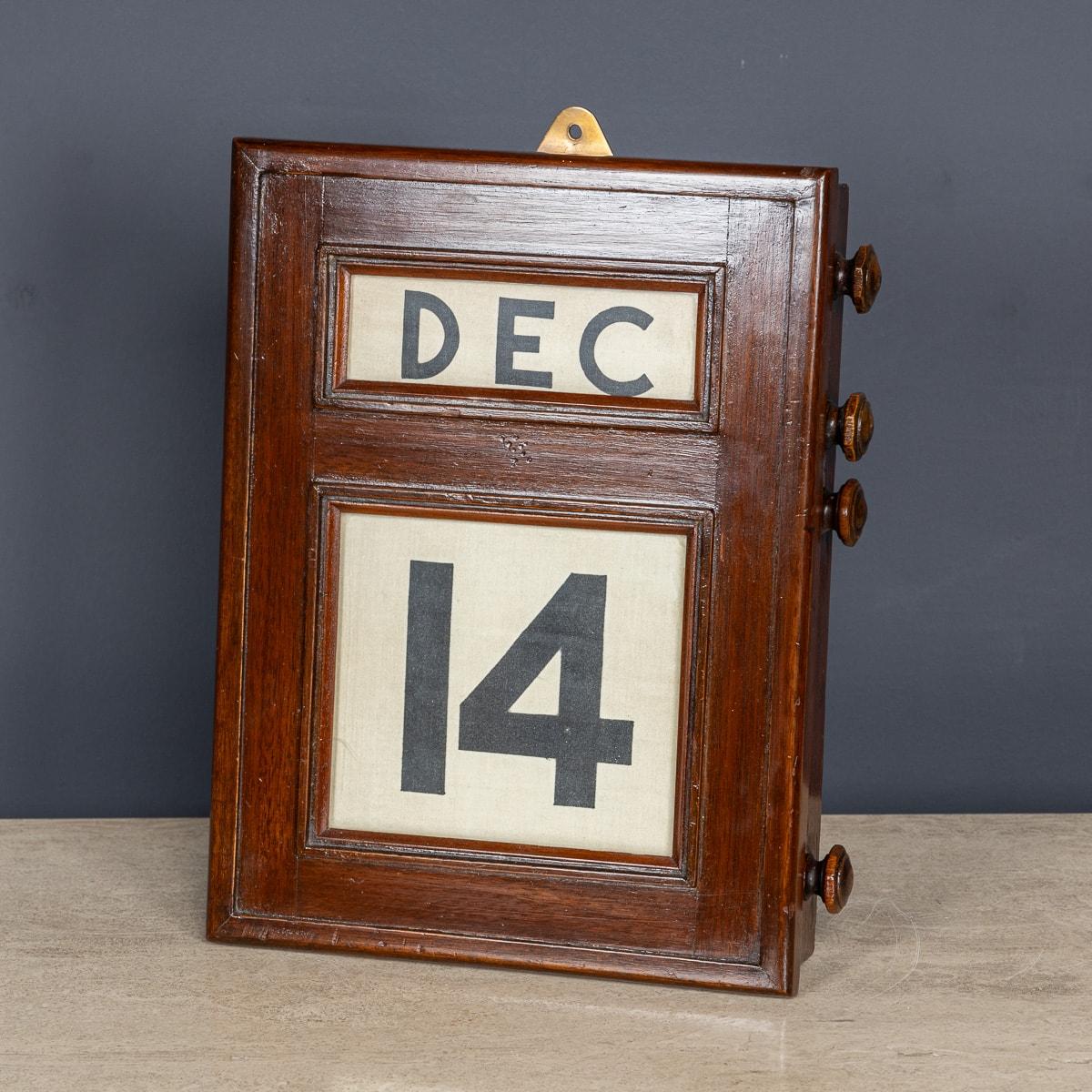 Ein hervorragender Tischkalender des 20. Jahrhunderts aus Mahagoniholz, der immerwährend ist. Auf einer Seite befinden sich vier Knöpfe, mit denen man hinter drei verglasten Blenden den Tag und das Datum vor- und zurückspulen kann. Auf der Rückseite
