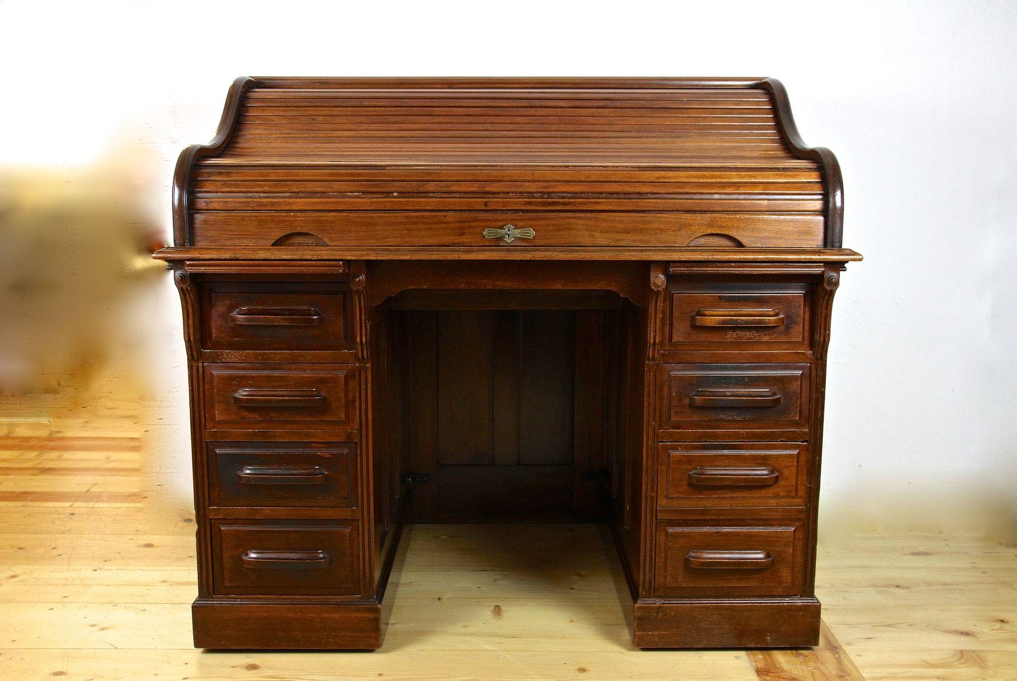 Beautiful mahogany roll top writing desk from the period around 1920 in England. An impressive example of an early 20th century knee hole desk which has been elaborately crafted by showing fine mahogany veneered surfaces. This fantastic office desk