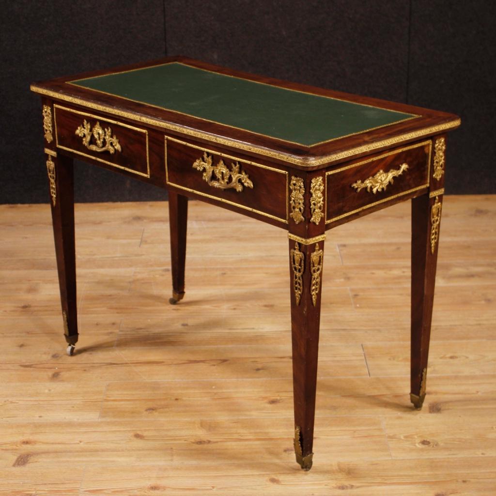 Early 20th century French writing desk. Mahogany wood furniture richly adorned with gilded and chiseled brass and bronze. Desk of small measure, finished for the centre, with two front drawers and a working key. Furniture supported by four legs