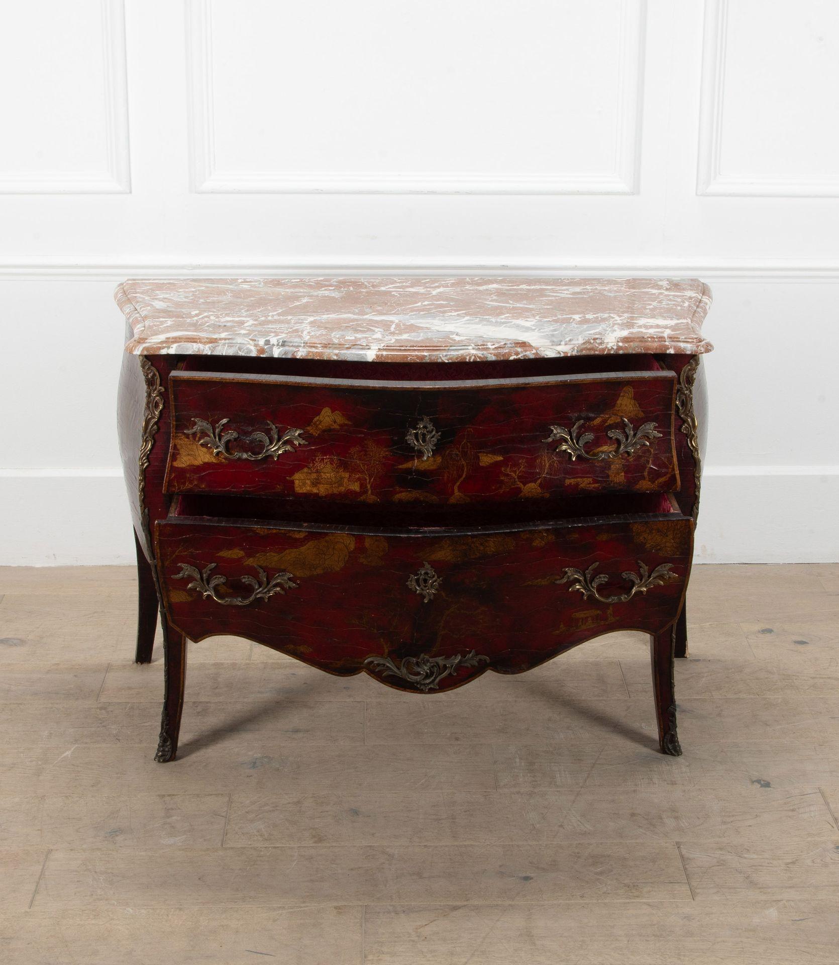 A striking 1950s French, Maison Jansen style, red lacquer and marble topped chinoiserie commode.
The red lacquer decorated with gilt chinoiserie figures and pavilions in a wooded landscape.
The sides with vases of flowers and foliage.
Finished with