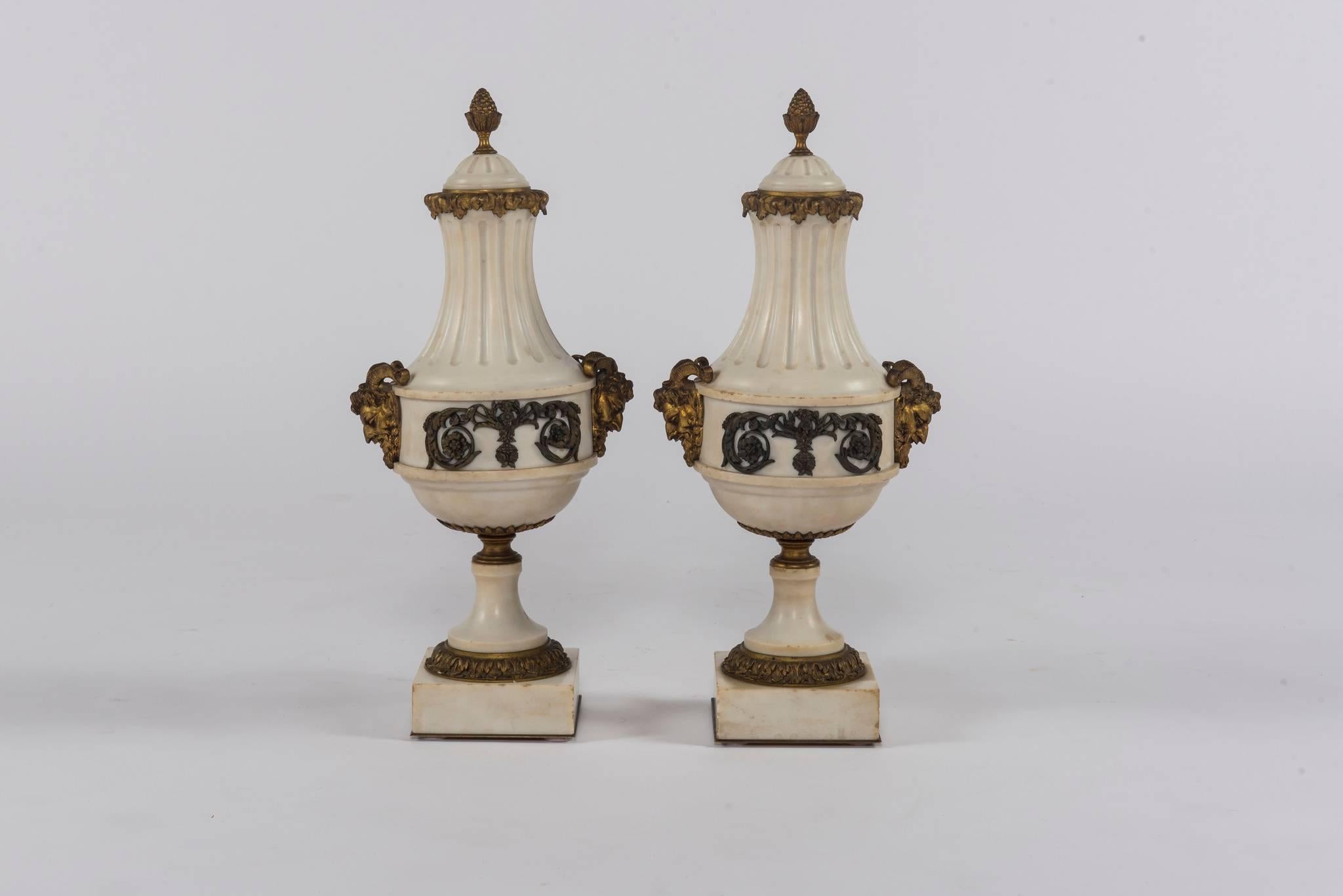 A pair of 20th century marble and bronze cassolettes featuring floral swags and satyr heads.