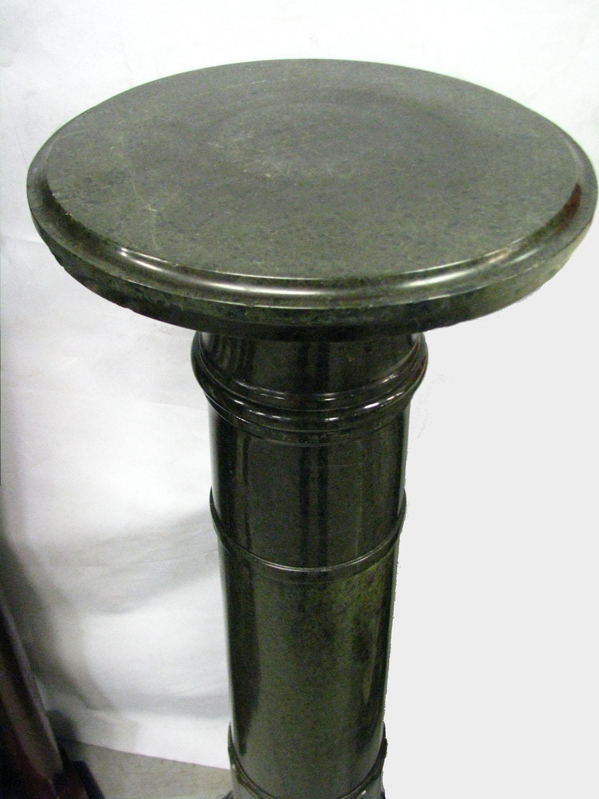 A Classic pedestal, meter high, made of bottle green marble, in the form of a column with a round, mostly smooth shaft, crowned with a round stone top.
Pedestal maintained in a classicist spirit.
Despite the relatively simple form - very
