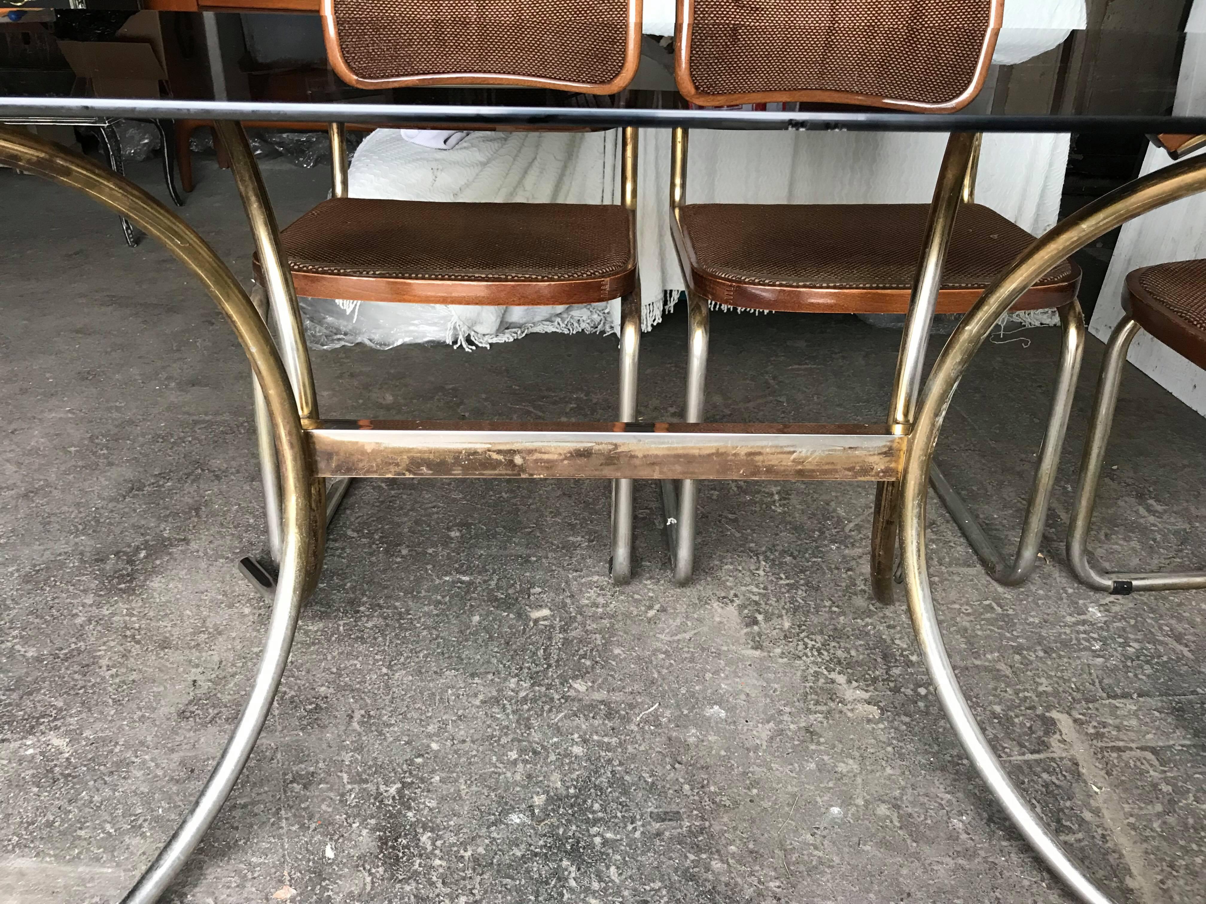 Bauhaus conference or dining set

Smoked glass table with brass pedestal base.
A set of 6 original Marcel Breuer Cesca style dining chairs from the 1980s. Upholstered in a soft brown checked fabric, these gold chromed cantilever chairs are super