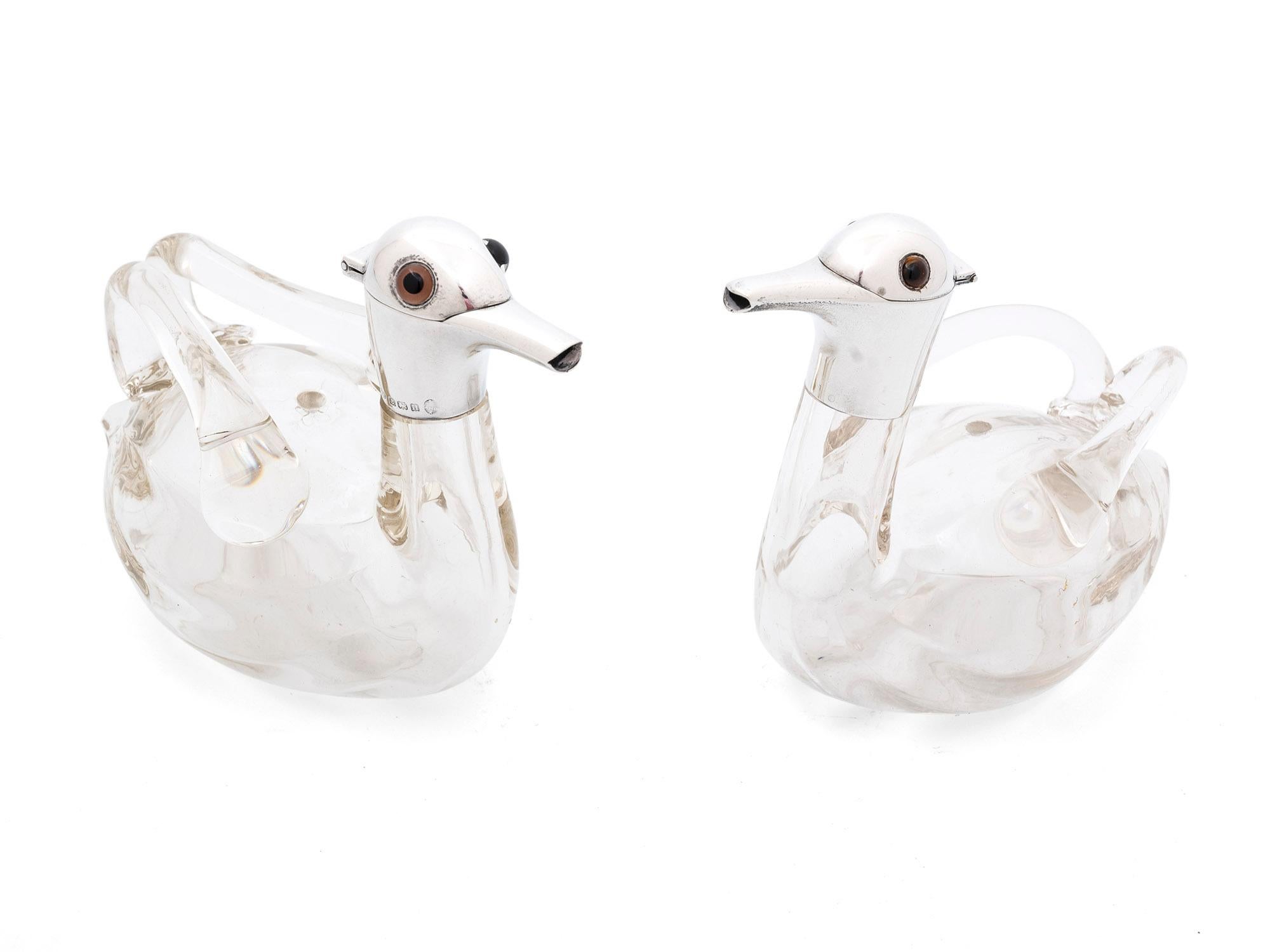 Dieses Zwillingspaar gläserner Entenkaraffen wurde für die Aufbewahrung von Likör verwendet. Mit ihren glänzenden Sterling-Silberkappen sind diese charmanten kleinen Enten-Dekanter mit einigen schönen Eigenschaften ausgestattet.

Jeder Dekanter hat