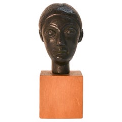 20th century miniature black terracotta head of a woman, mounted on wood