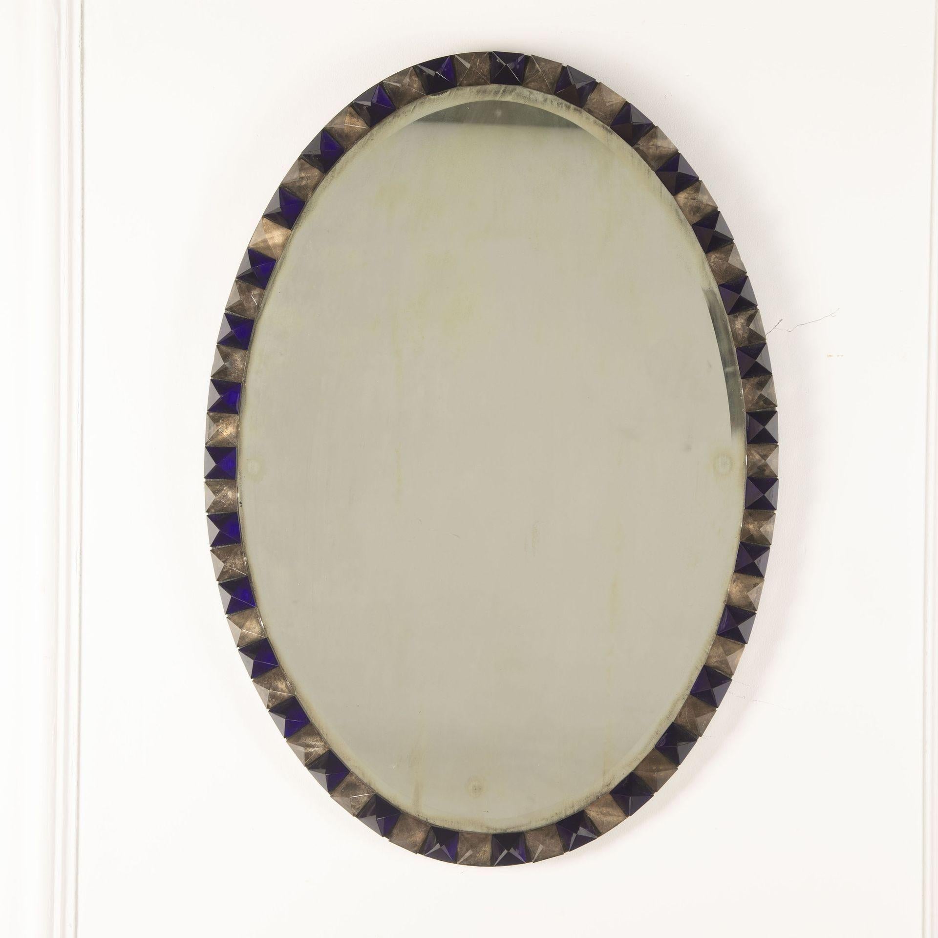 Mid 20th century mirror within an indigo and clear glass segmented frame.
Wear to mirror consistent with age.