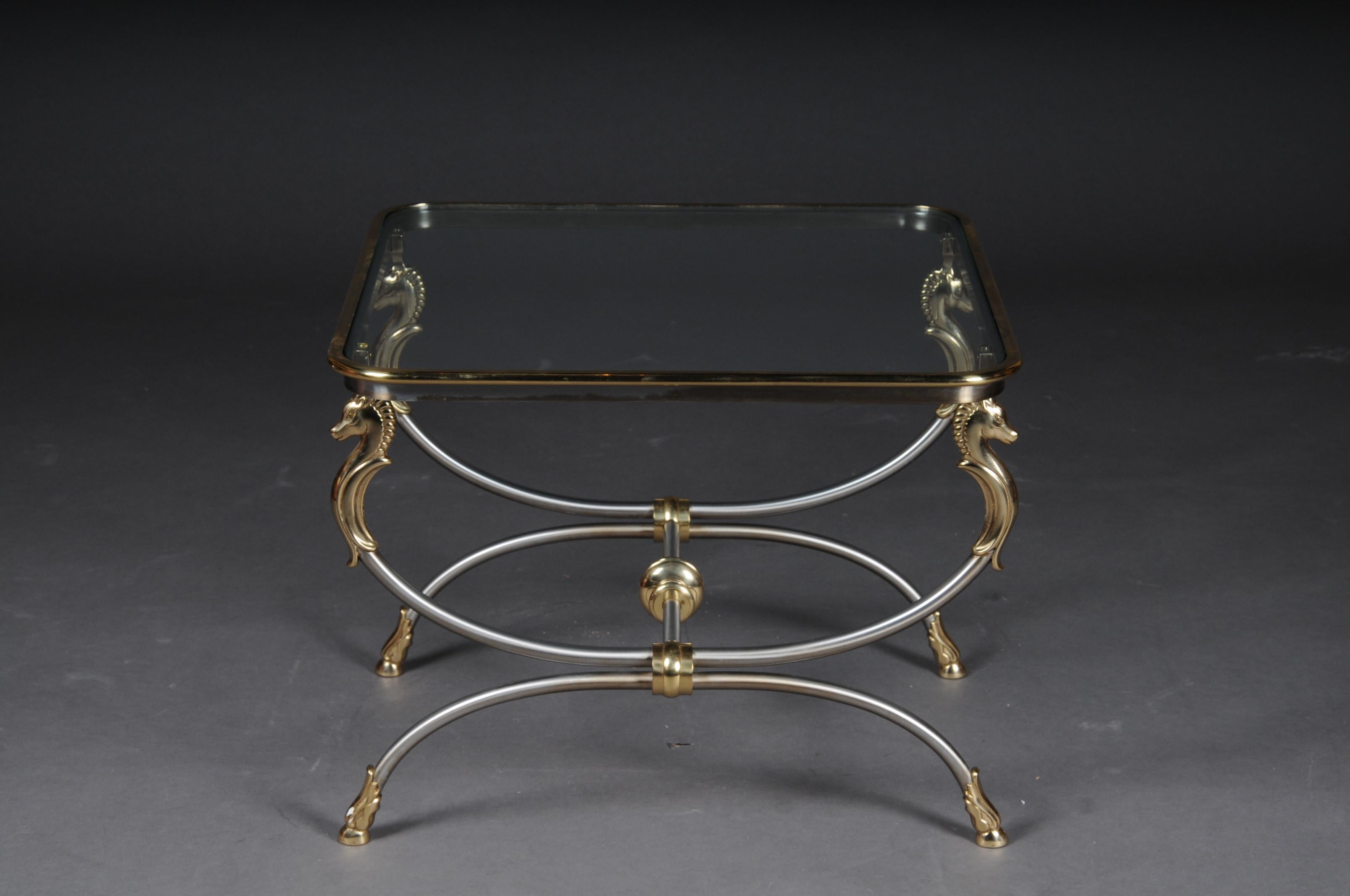20th century modern designer side table, chrome brass, classical style

Chrome / brass frame, curved and flanked by horse busts in brass. Polished brass frame enclosed in a glass plate.

(A-168).
