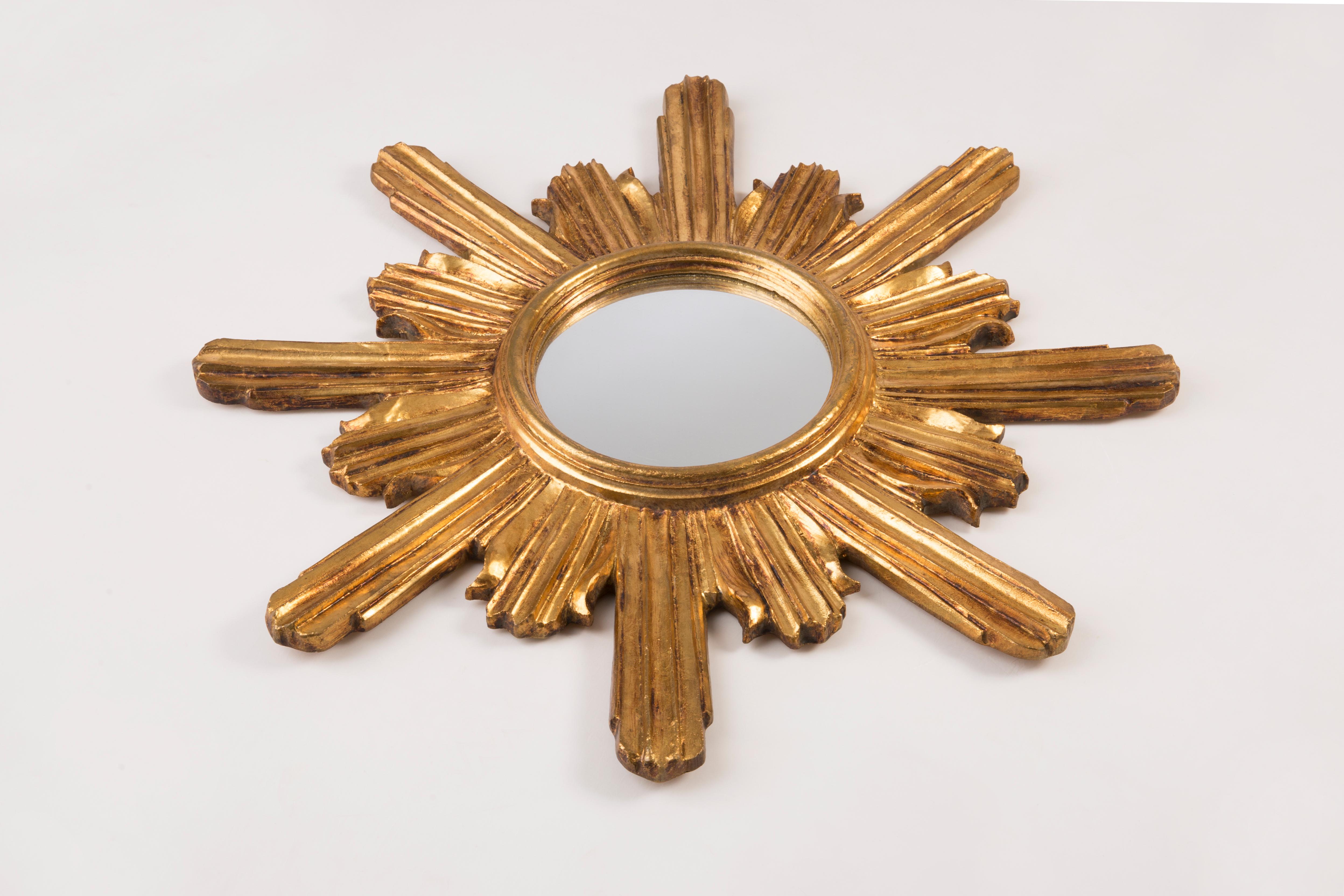 A mirror in a golden decorative sun-shaped frame from Italy. The frame is made of wood. Very good condition, no damage or cracks in the frame, the mirror pane has minimal flaws. Beautiful piece for every interior! Mirror size: 20cm, frame size: 60cm.