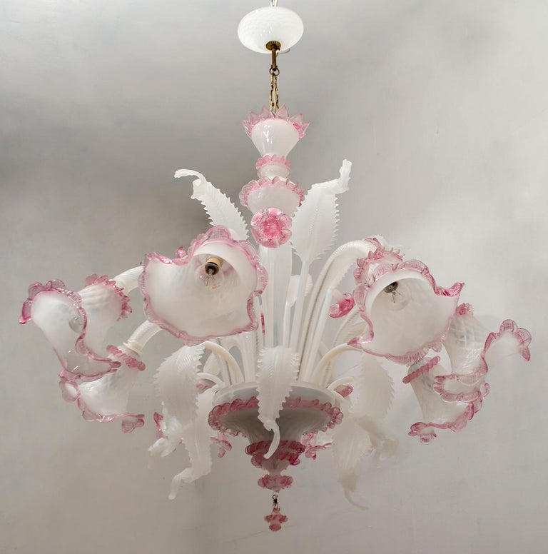 An elegant eight-light chandelier in milk-colored Murano glass and sophisticated fuchsia pink finishes. With a centered bulbous column that emits branches and flowers and finely cuts the Murano glass leaves.

