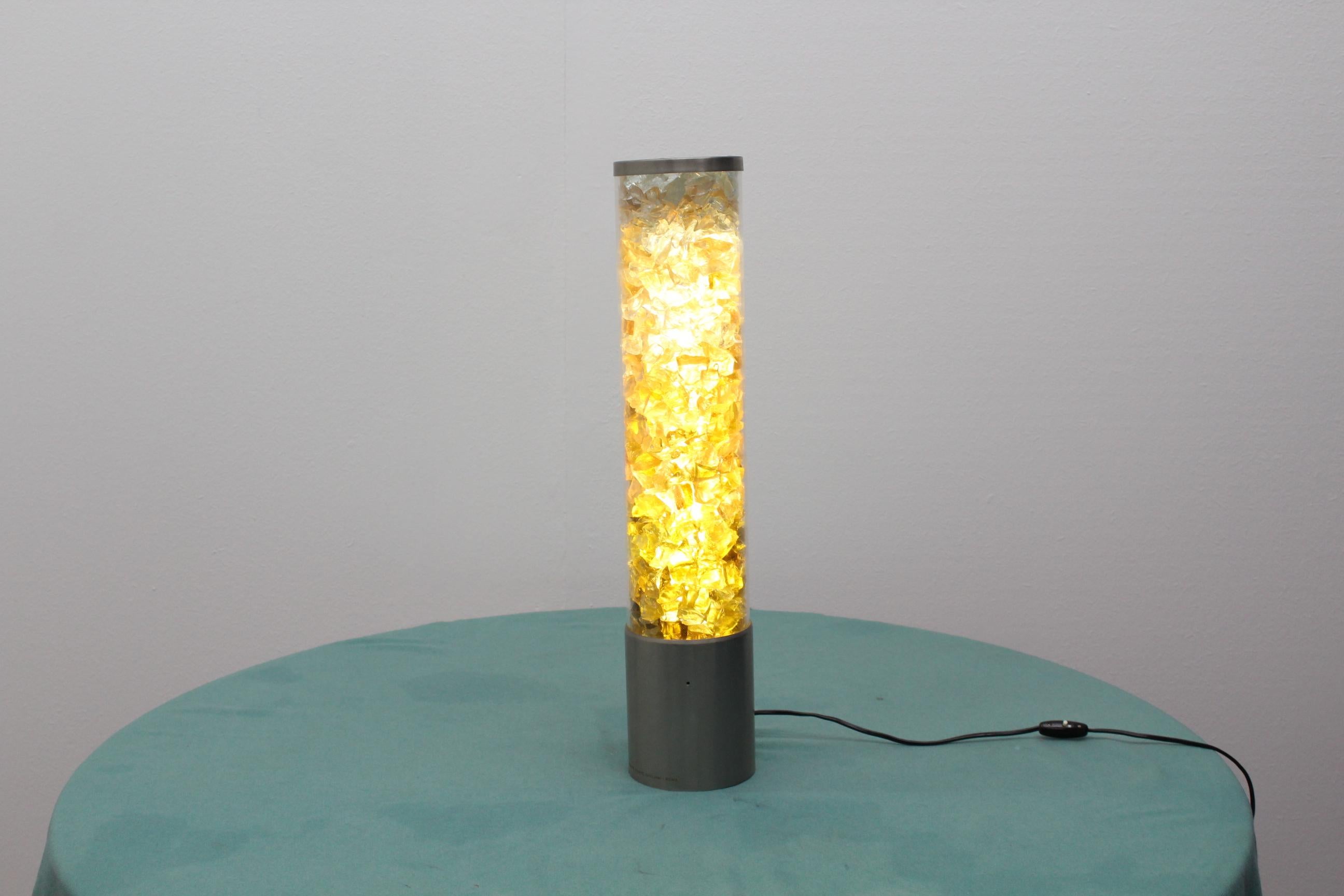 Particular floor lamp composed by a perspex tube with the inside full of multi-color fragment of glass in through which the light it's diffused. Produced by the Historical 